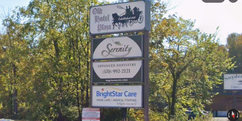 Outdoor signpost with BrightStar Care and Serenity Dentistry signs among trees.