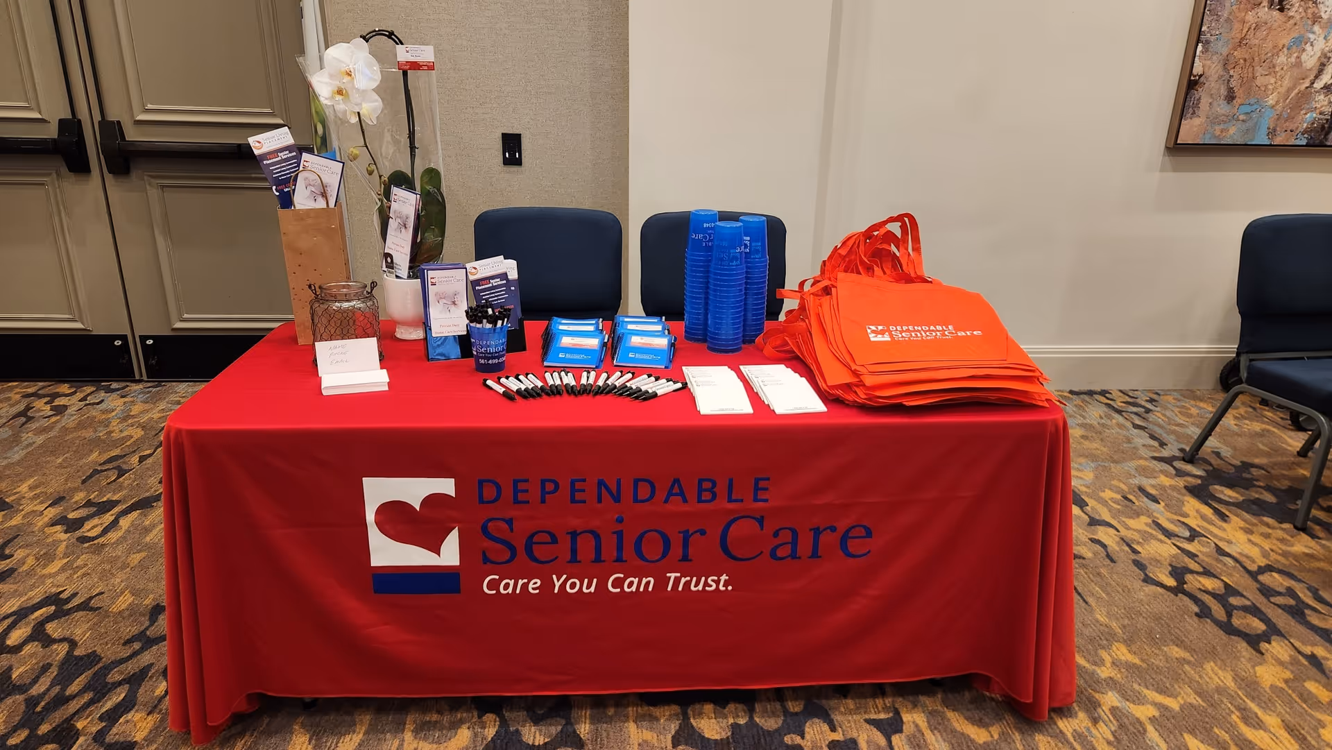 Promotional table with a red cloth and Dependable Senior Care materials in an interior setting.