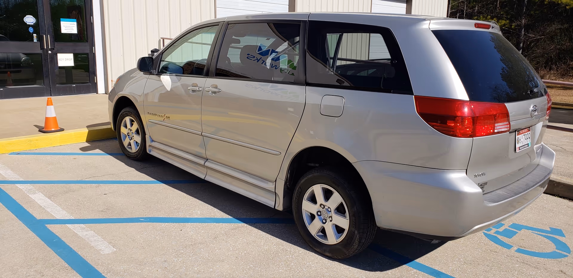Silver minivan parked in a handicapped space near the building entrance at MobilityWorks