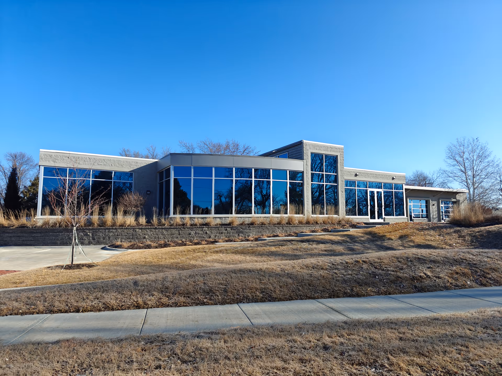 Amada Senior Care facility exterior with large glass windows and a clear blue sky.