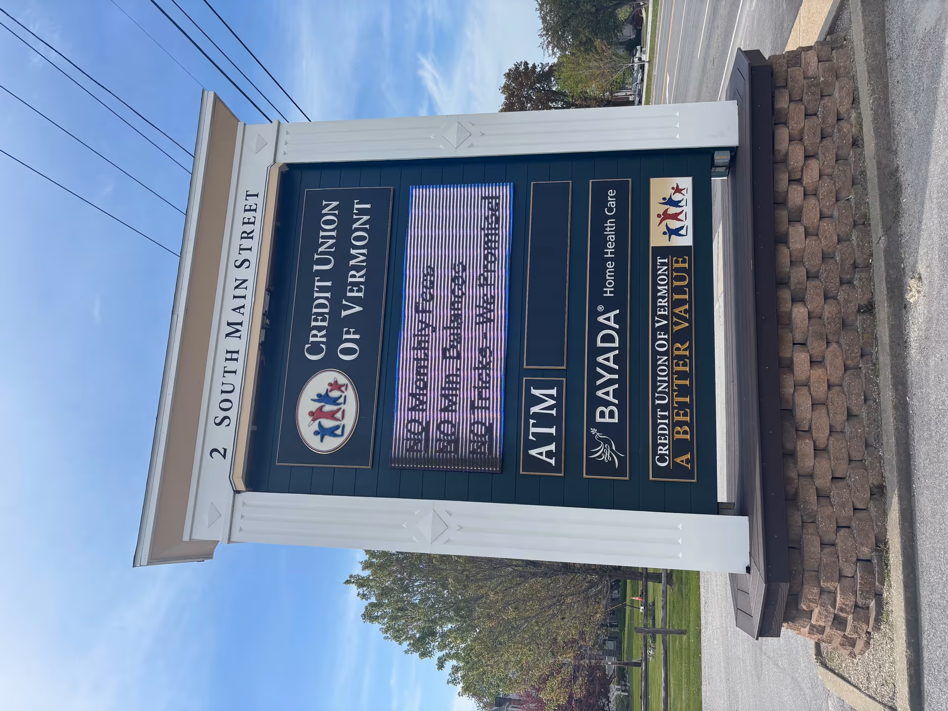 Vertical signboard displays BAYADA Assistive Care and Credit Union signs on Main Street.
