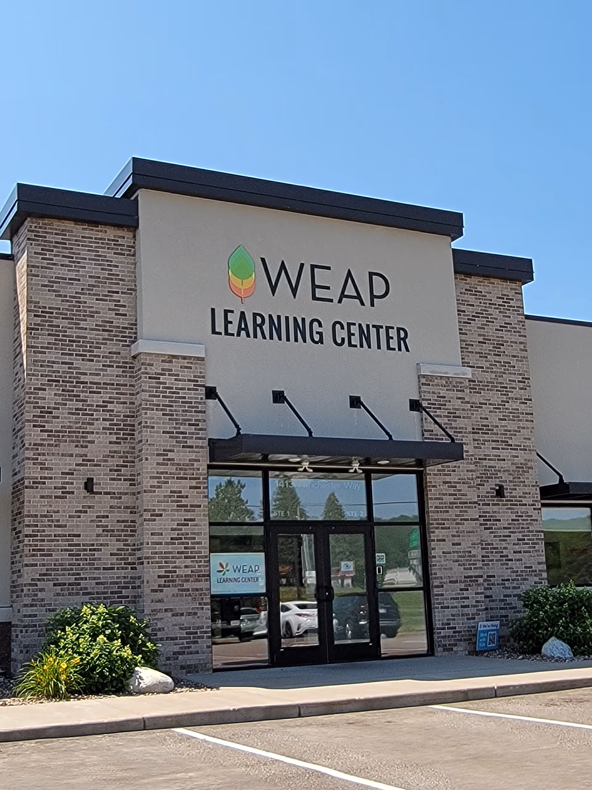 Front view of a brick building displaying WEAP Learning Center sign and parking.