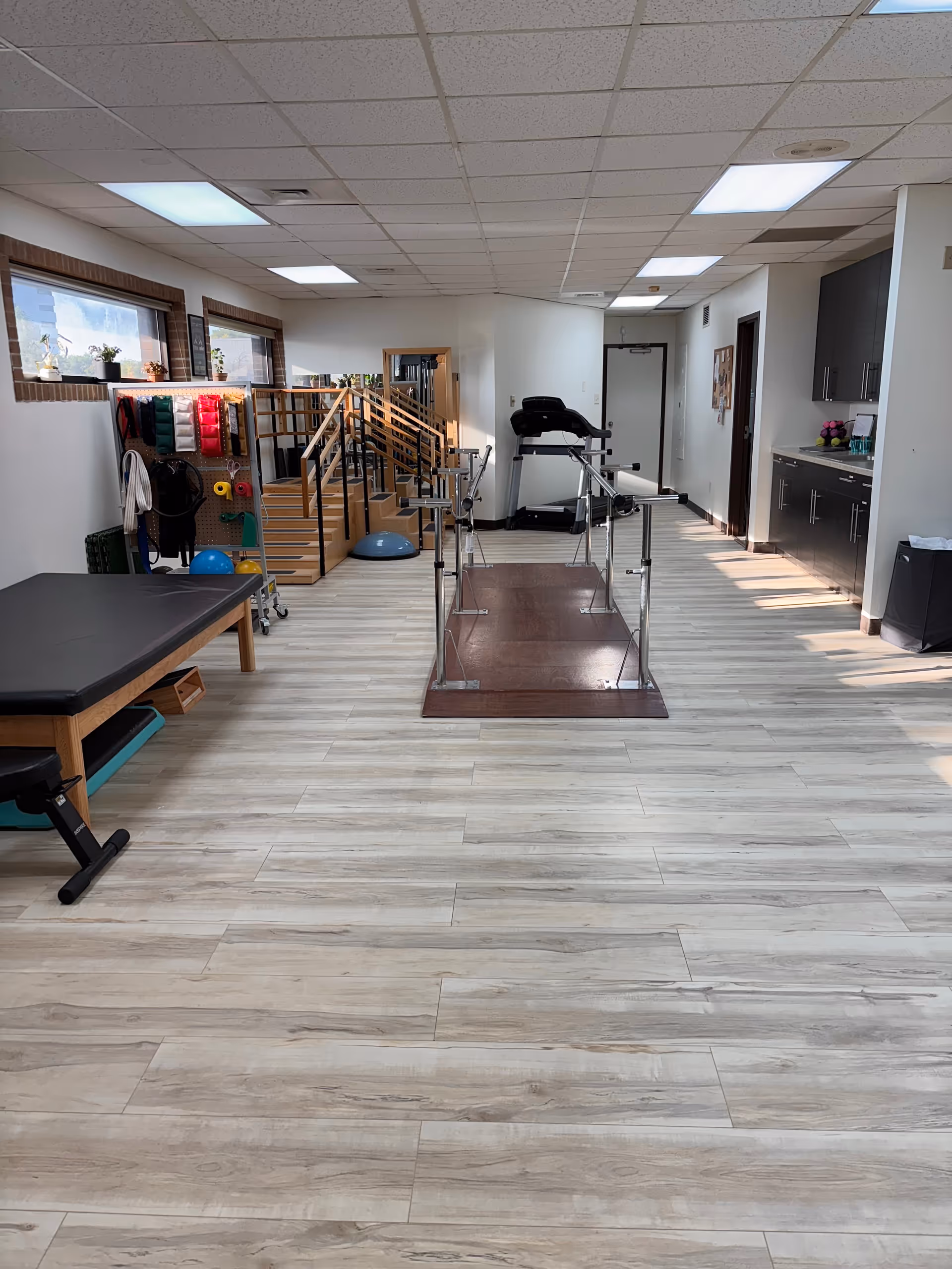 Interior therapy gym at Apex Physical Therapy Merrillville featuring parallel bars and exercise equipment.