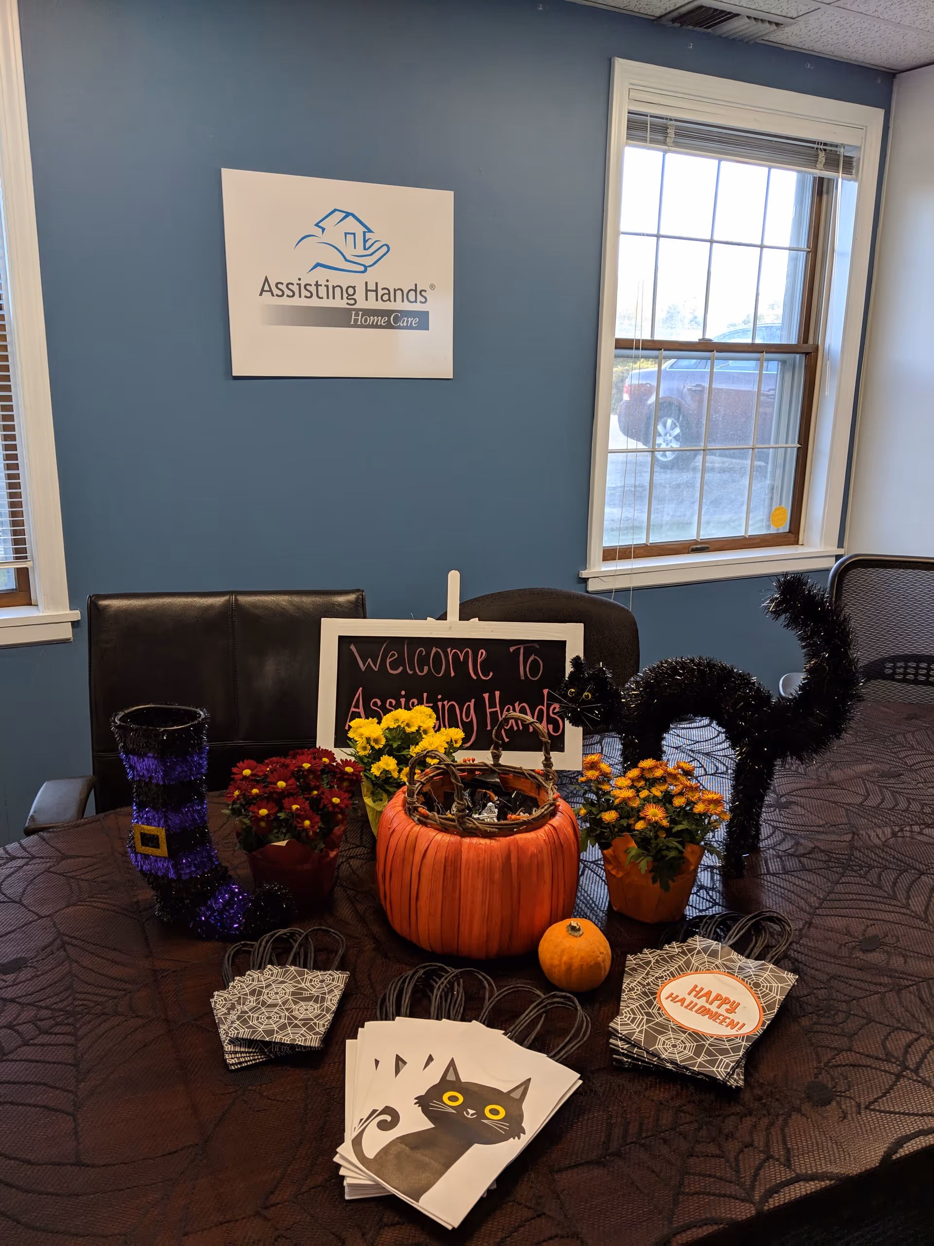 Indoor reception area with blue wall, Assisting Hands Home Care sign, and Halloween-themed decorations.
