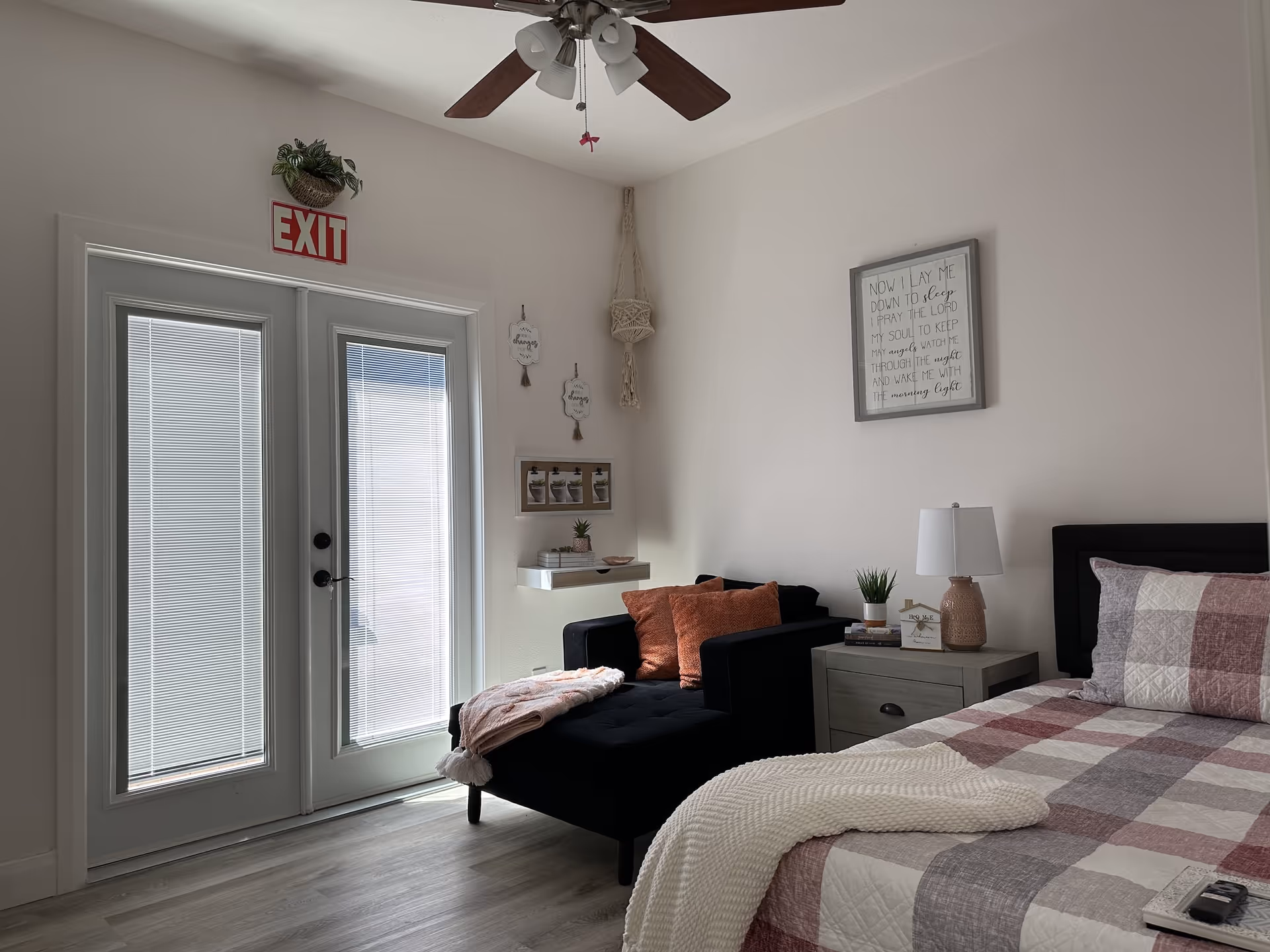 Cozy bedroom with bed, nightstand, sofa, lamp, ceiling fan, and glass exit door.