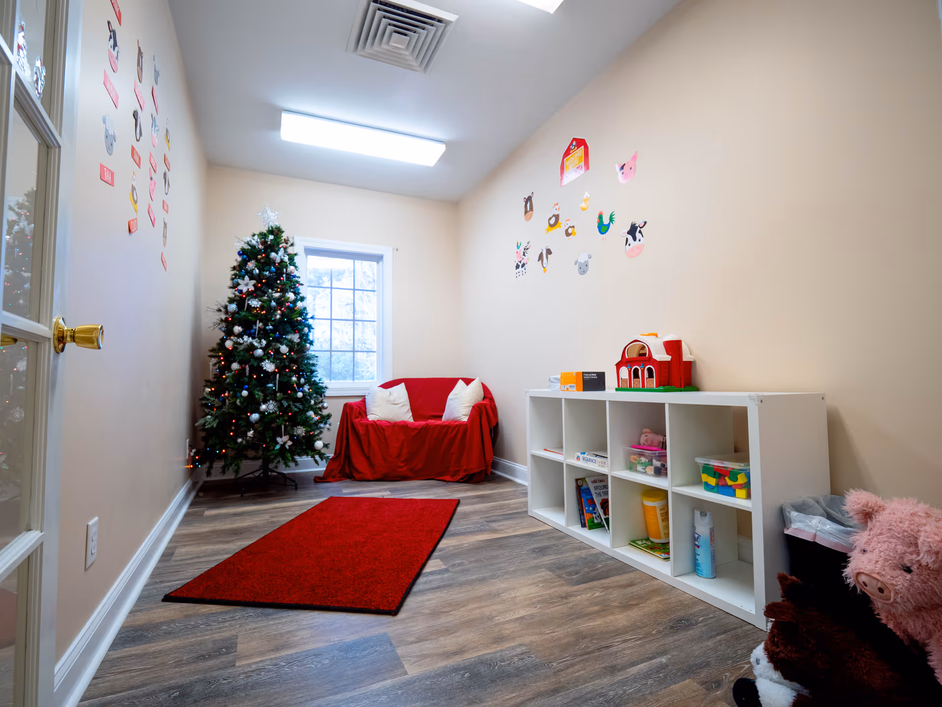 Cozy play area in a senior facility with a Christmas tree, red sofa, and cubby storage