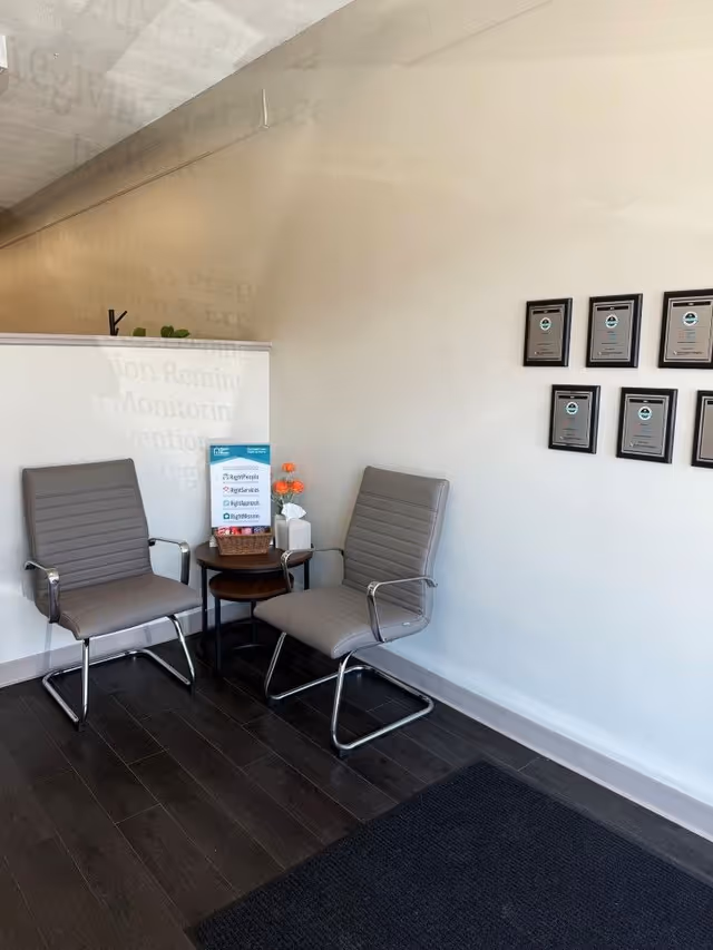 Two gray chairs flank a small round table in a modern reception area.