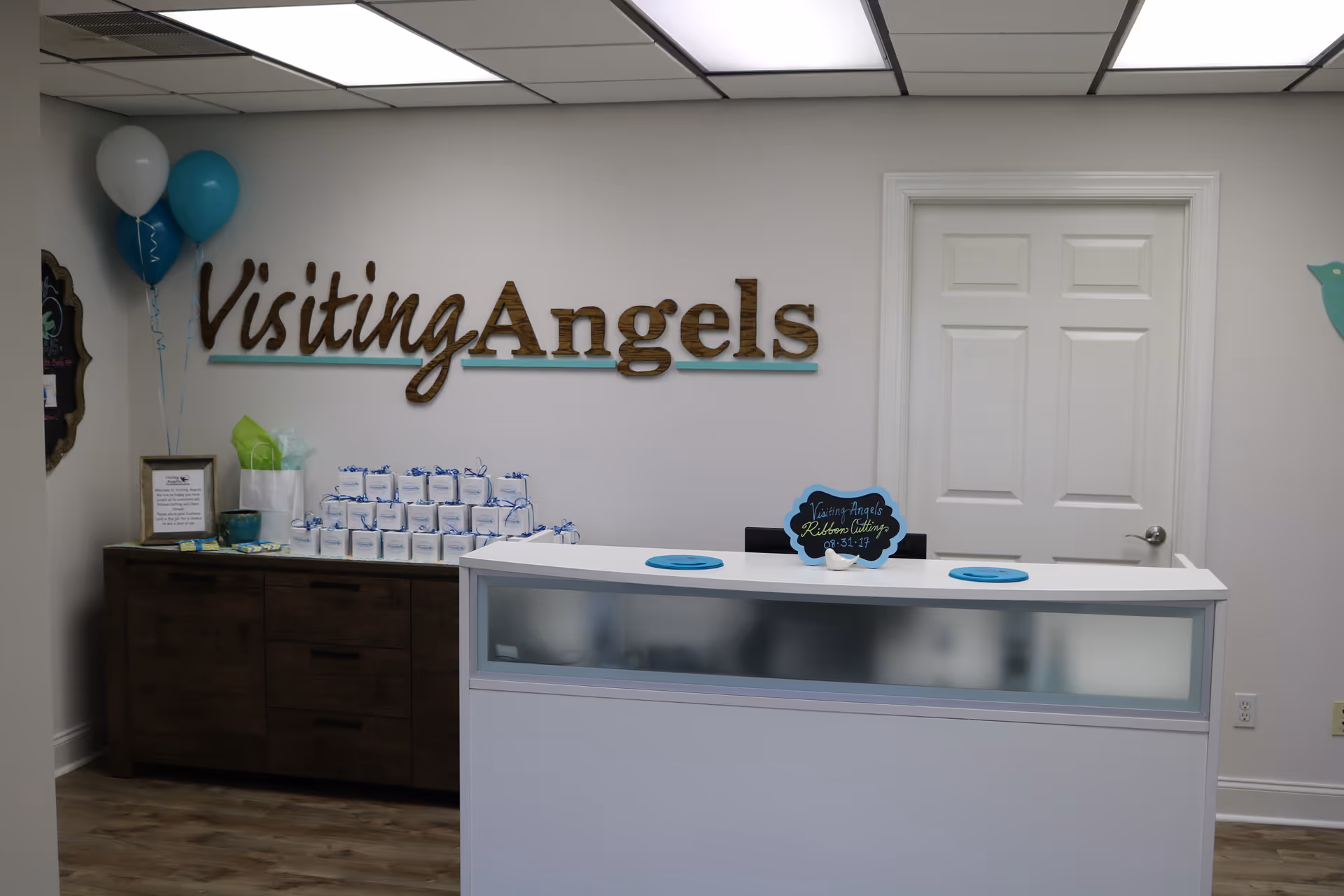 Reception desk in a bright lobby with a Visiting Angels sign and gift area.