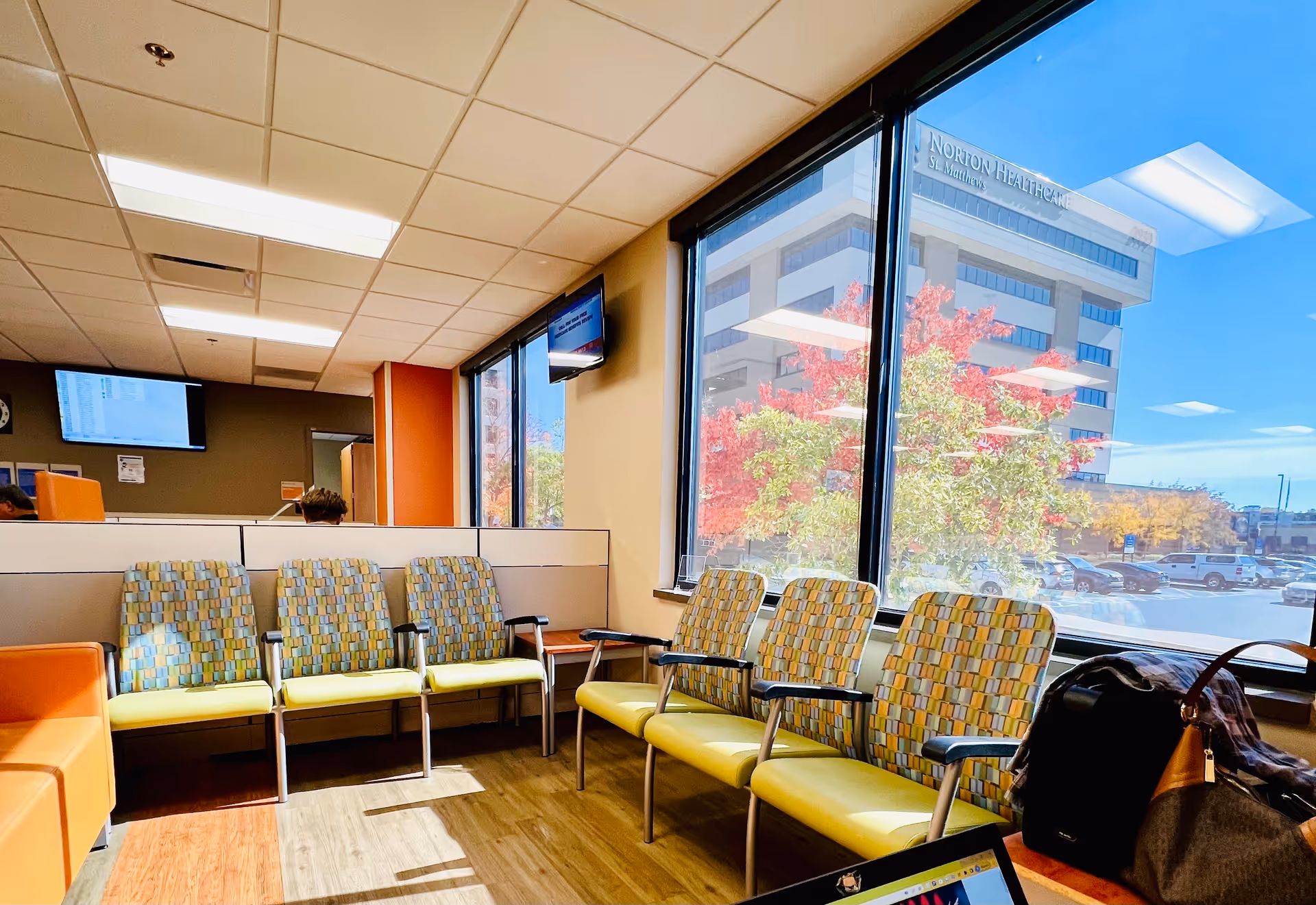 Lobby-style waiting area with colorful chairs along large windows.