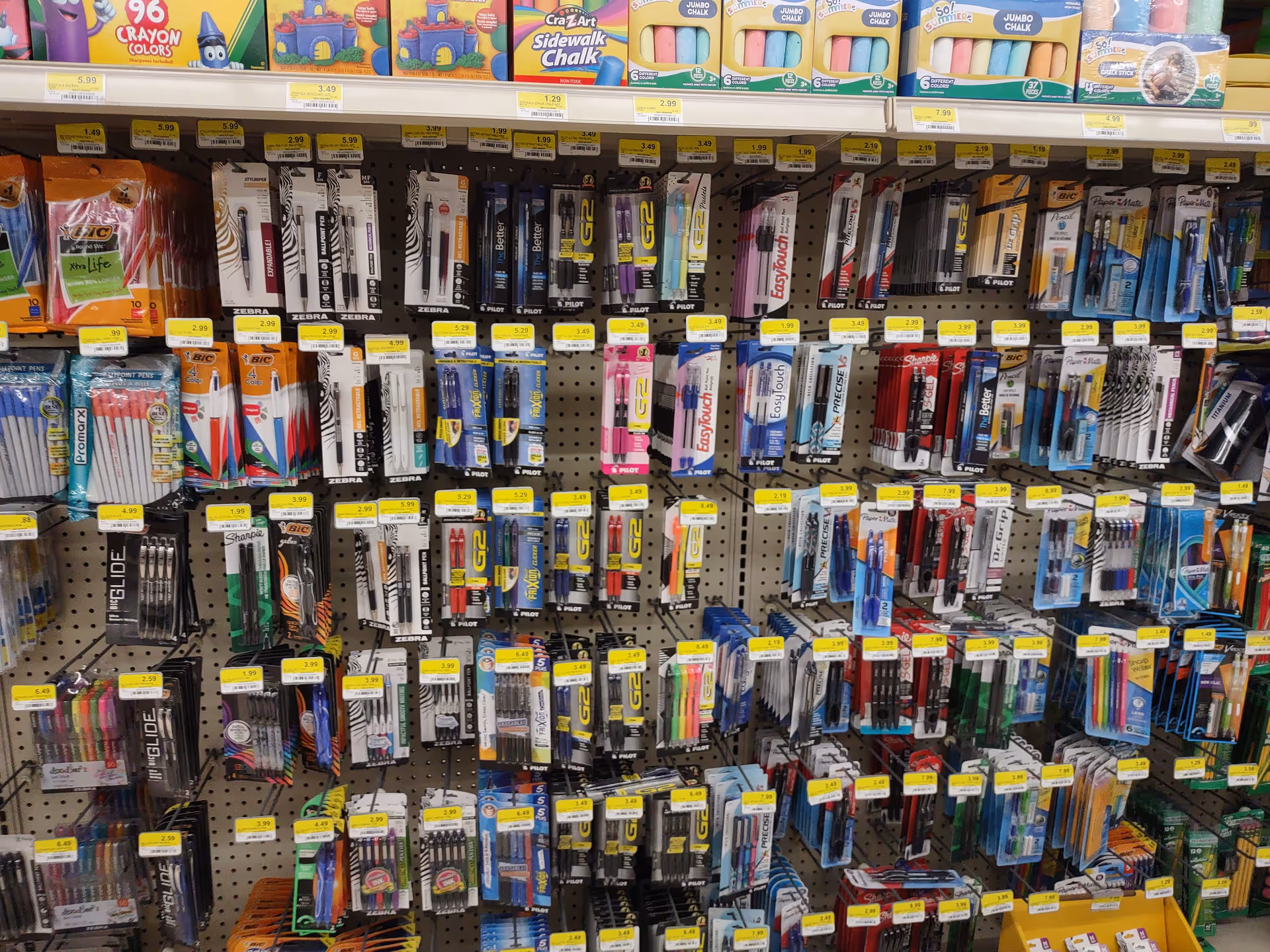 Retail display of assorted pens and stationery on pegboard shelves inside Discount Drug Mart