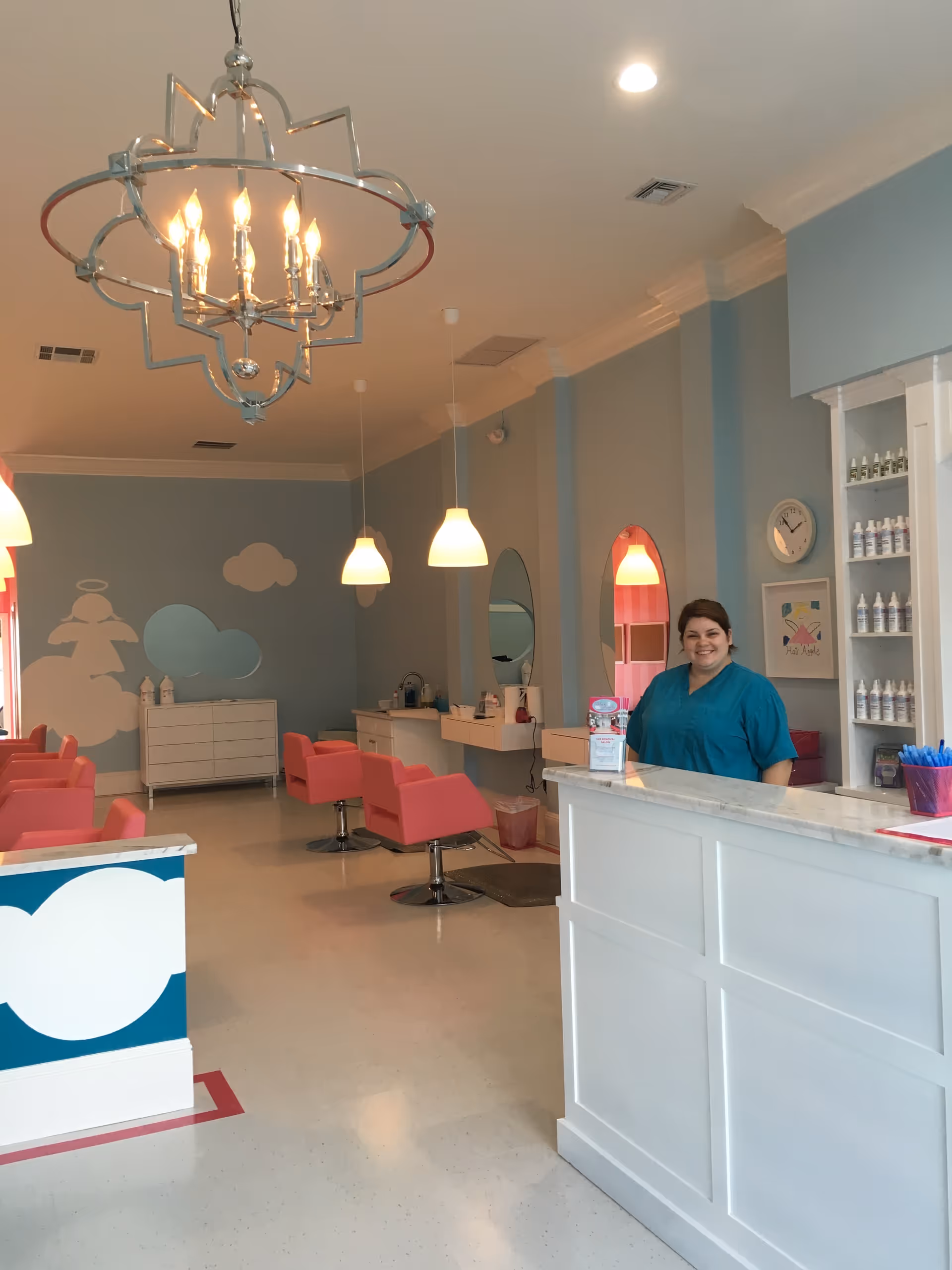 Pastel-colored salon interior with pink chairs, reception desk, and staff member in teal scrubs.