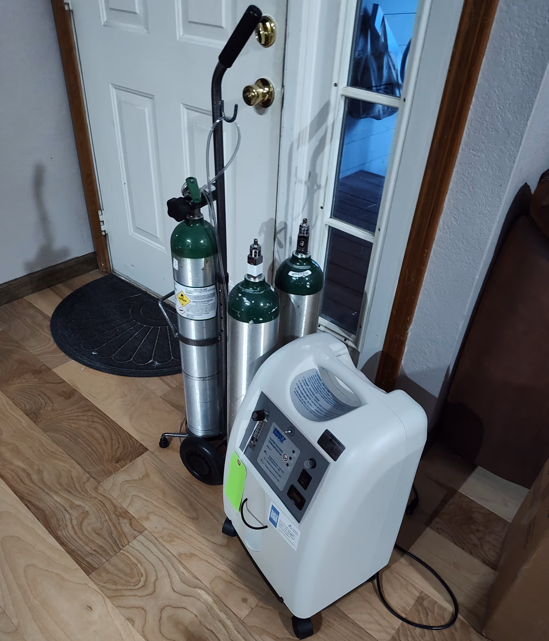 Oxygen tanks and a portable concentrator near a door inside a senior living facility.