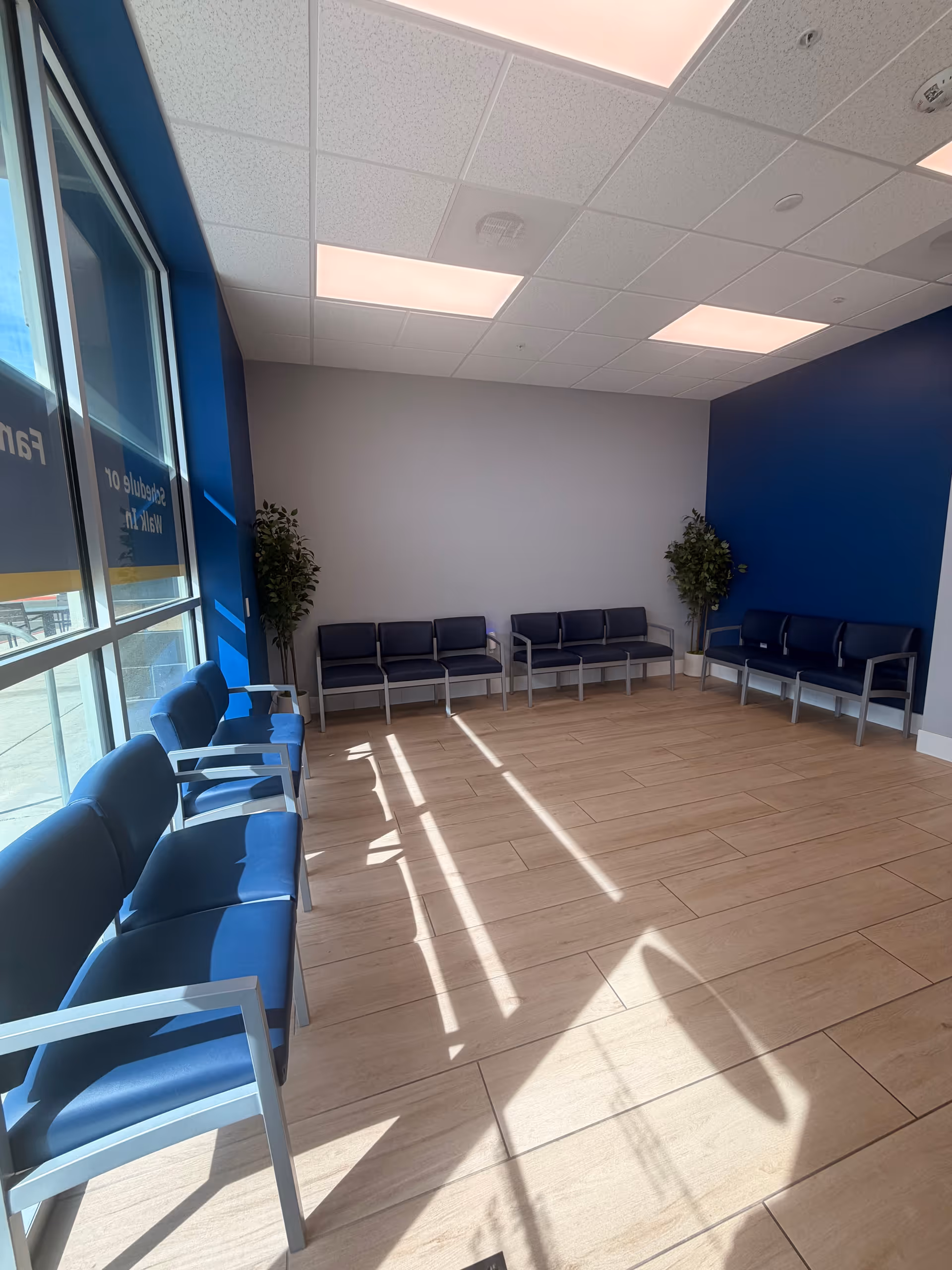 Empty waiting area interior with blue chairs along walls and windows