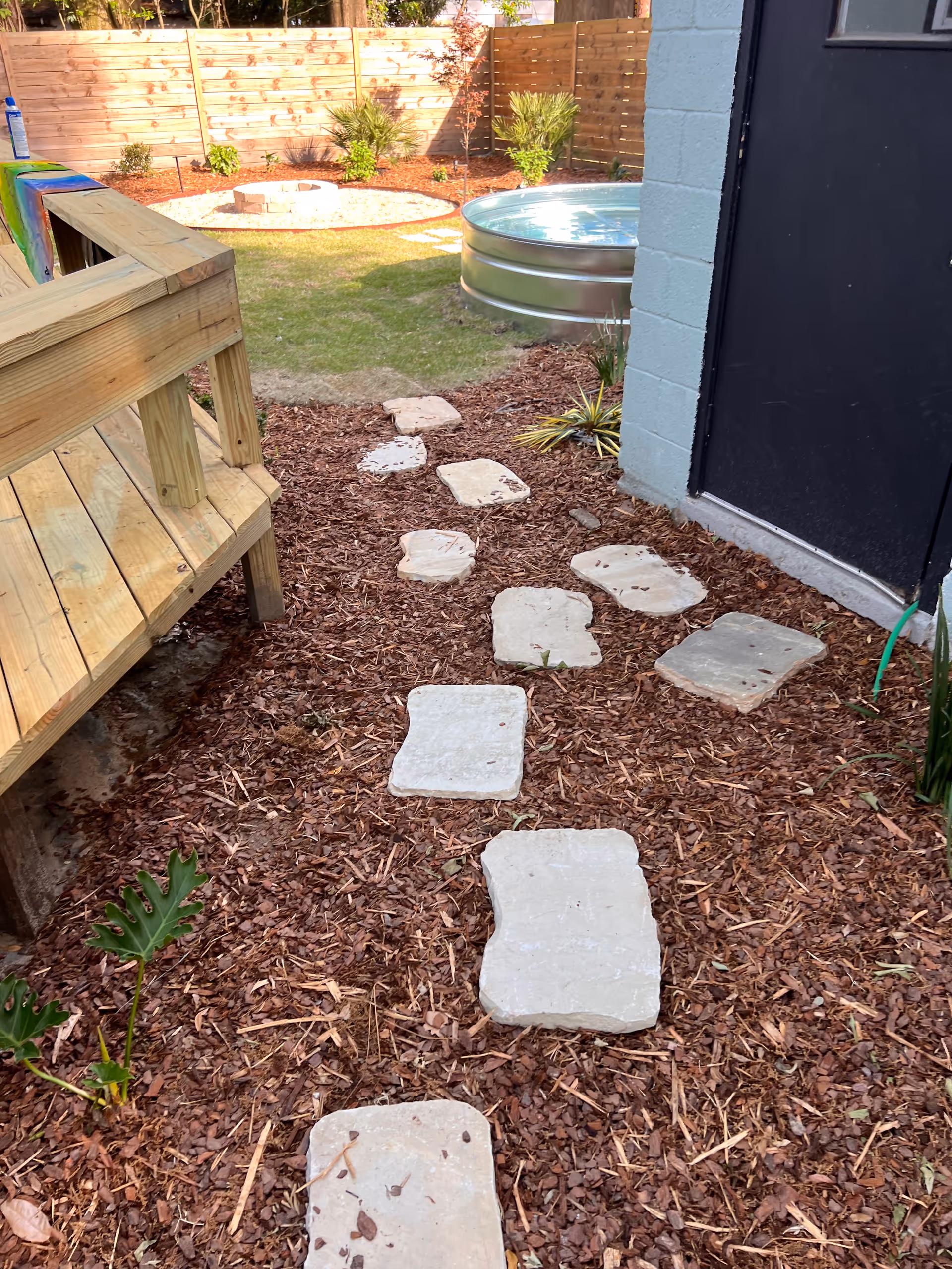 Outdoor yard of a senior facility with stepping-stone path, mulch, and a wooden deck.