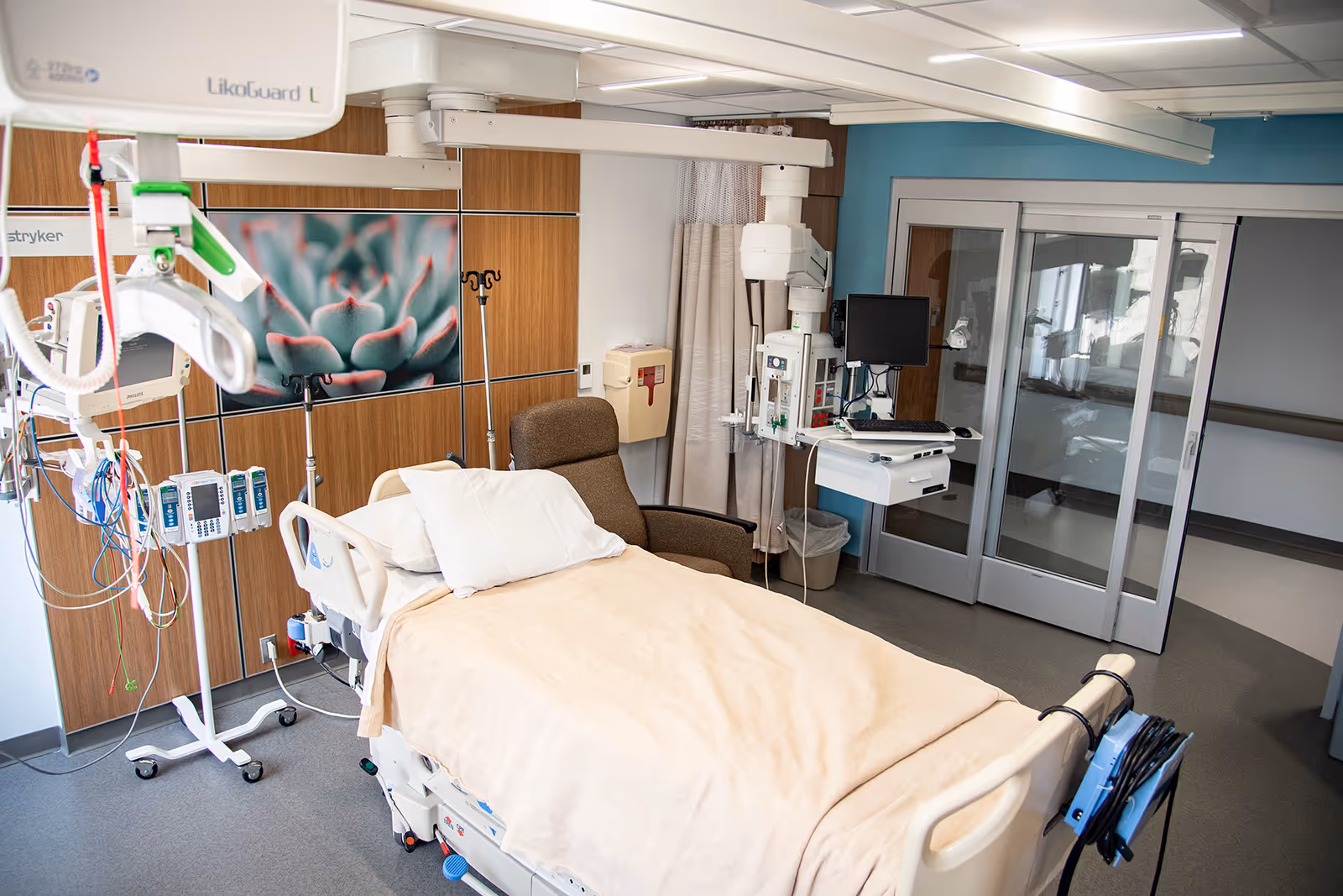 Hospital bed in a clinical patient room with IV lines, monitors, and equipment.