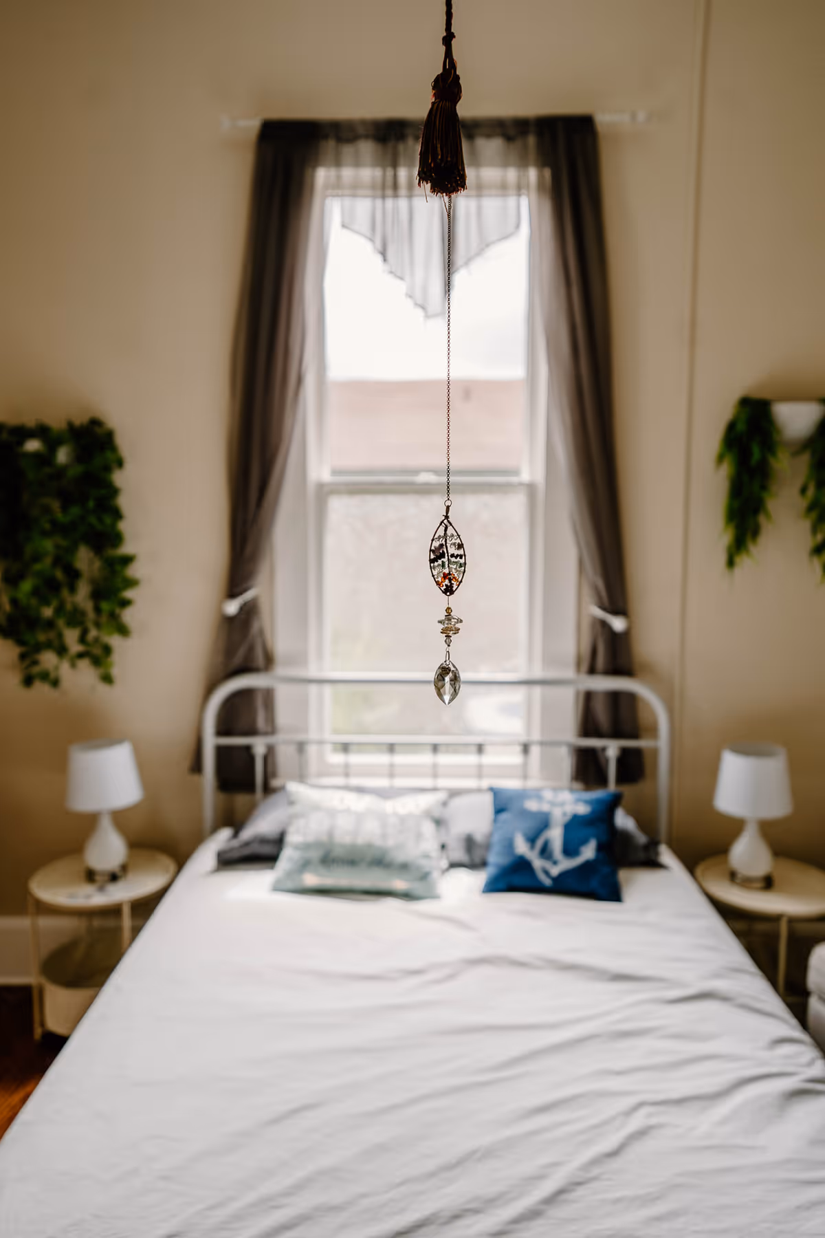 Bedroom with metal bed frame, two nightstands, lamps, and draped curtains.