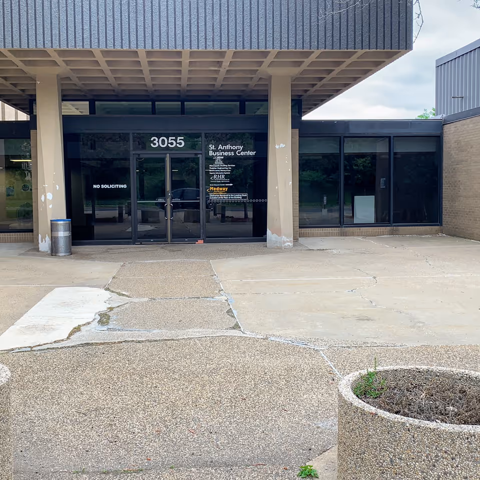 Front entrance of a building with glass doors under a large overhang.