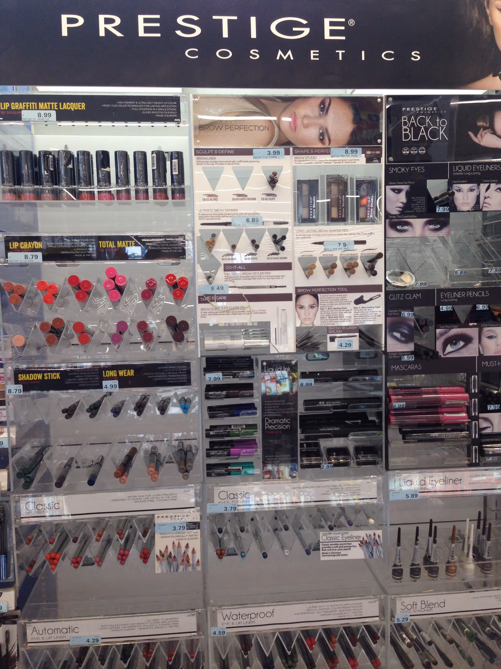 Cosmetics display wall with lipstick and makeup products branded Prestige Cosmetics in a store.