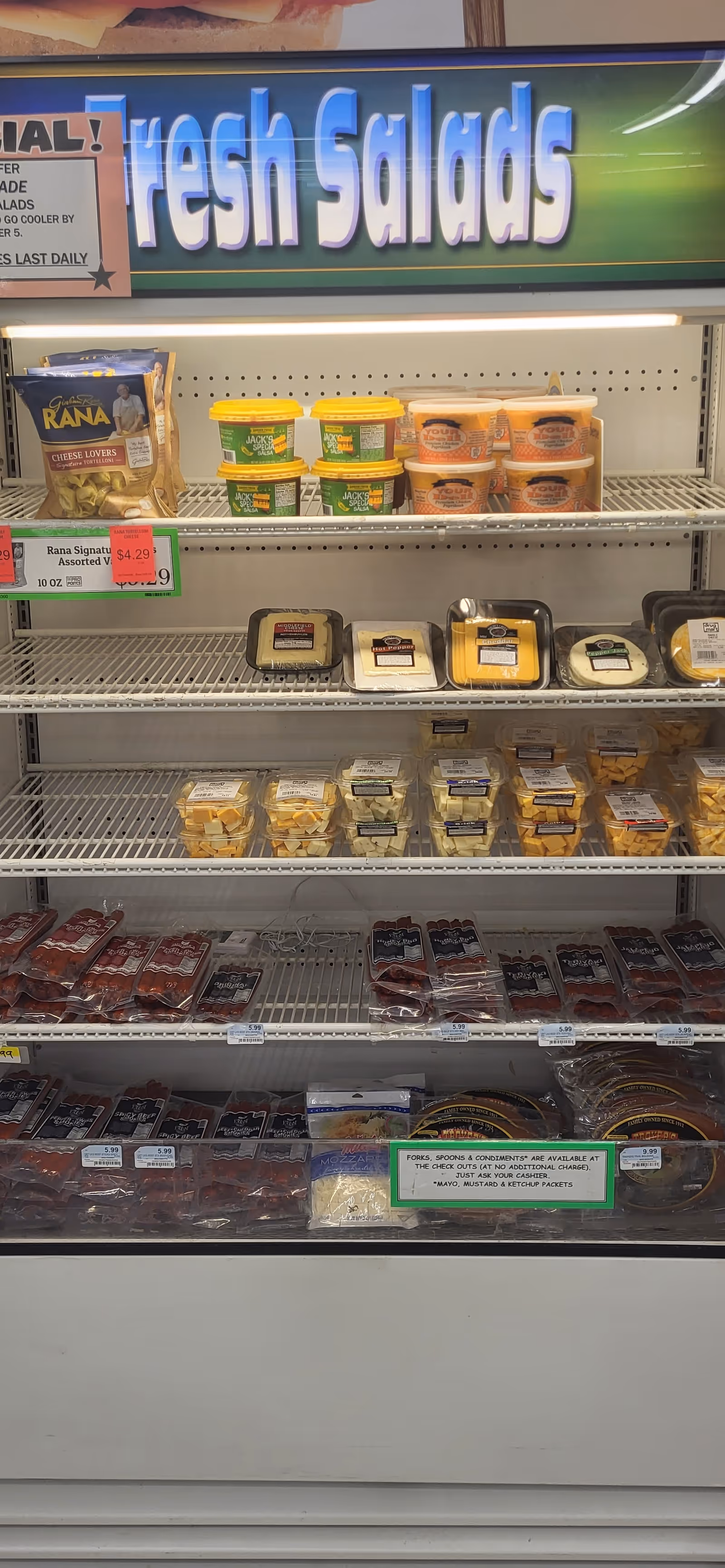 Refrigerated display case with fresh salads and deli items under a Fresh Salads sign.