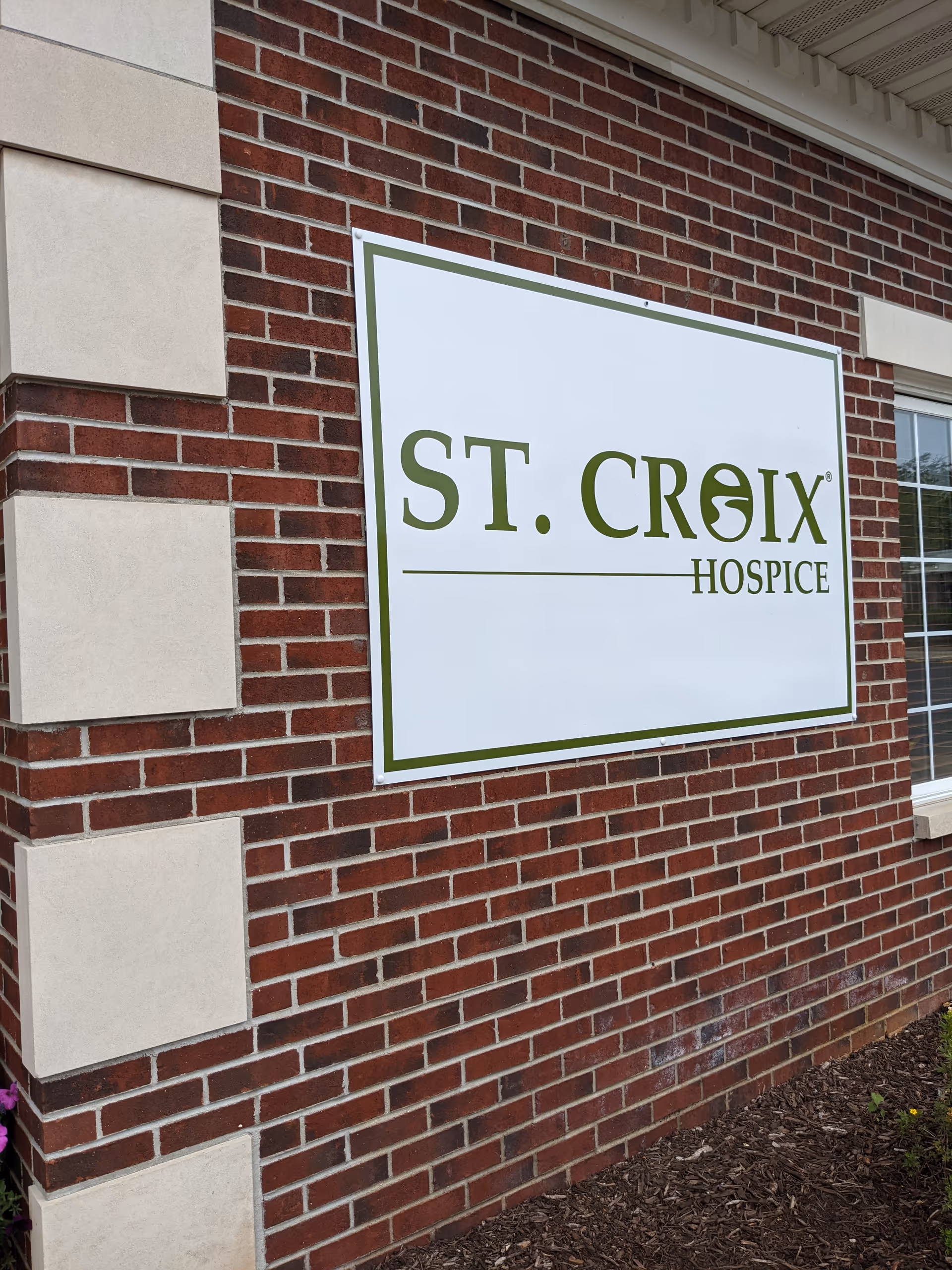 Brick exterior wall with a large ST. CROIX HOSPICE sign mounted.