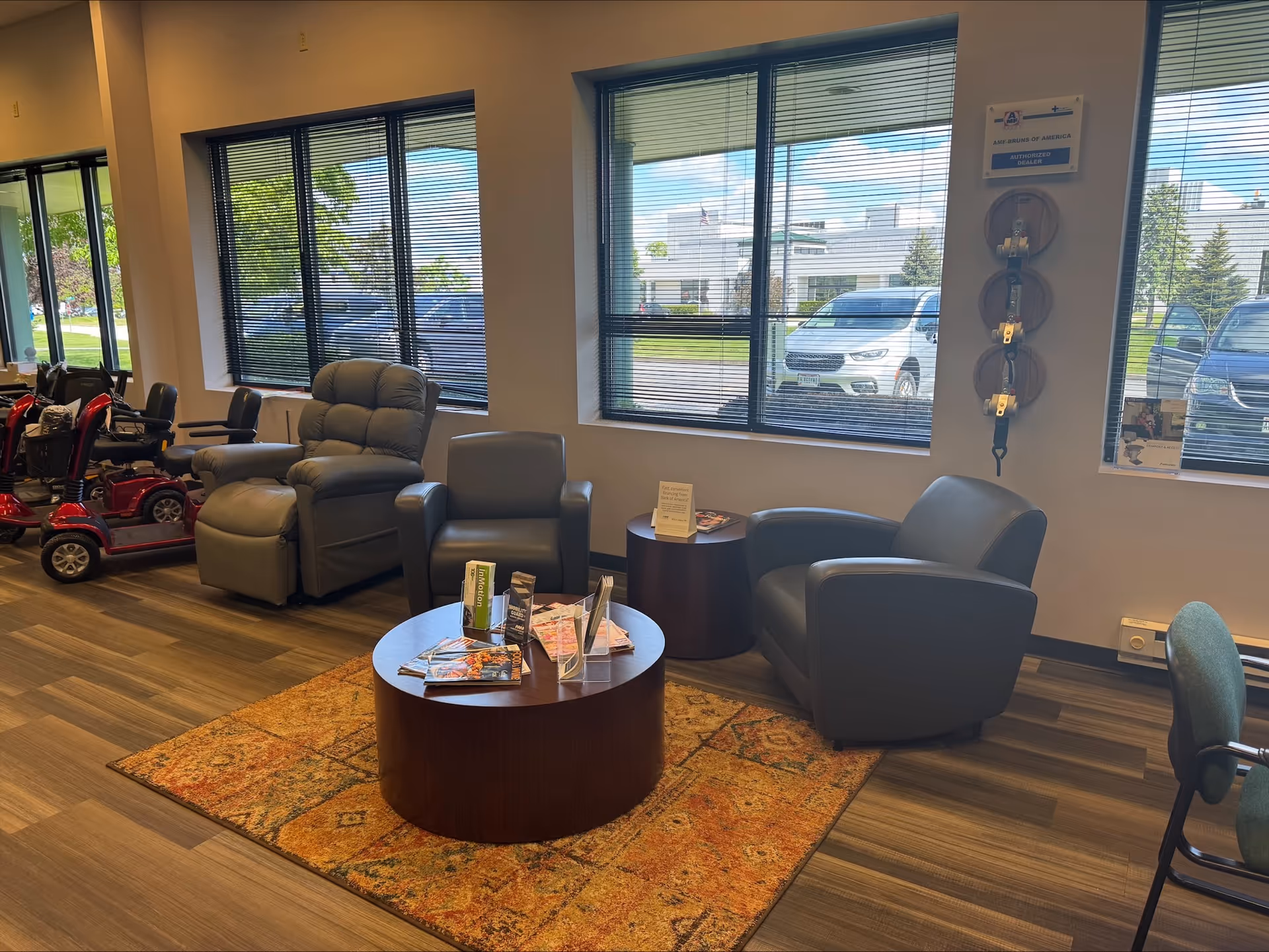 Senior living facility lounge with recliners, chairs, coffee tables, and large windows.