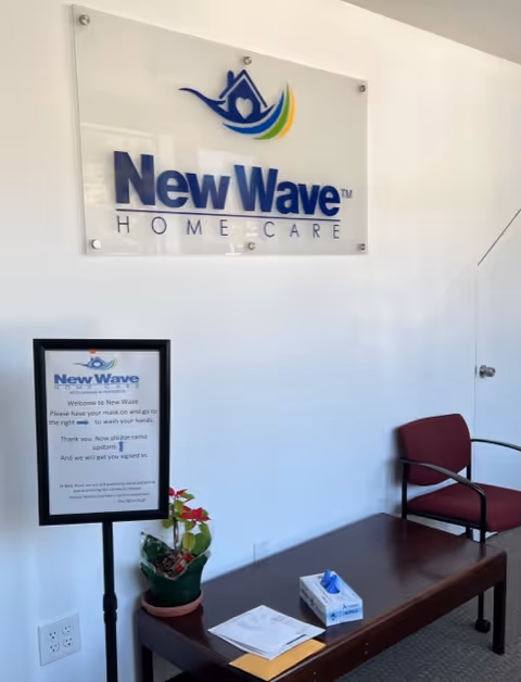 Interior lobby of New Wave Home Care with wall sign, chair, and coffee table.