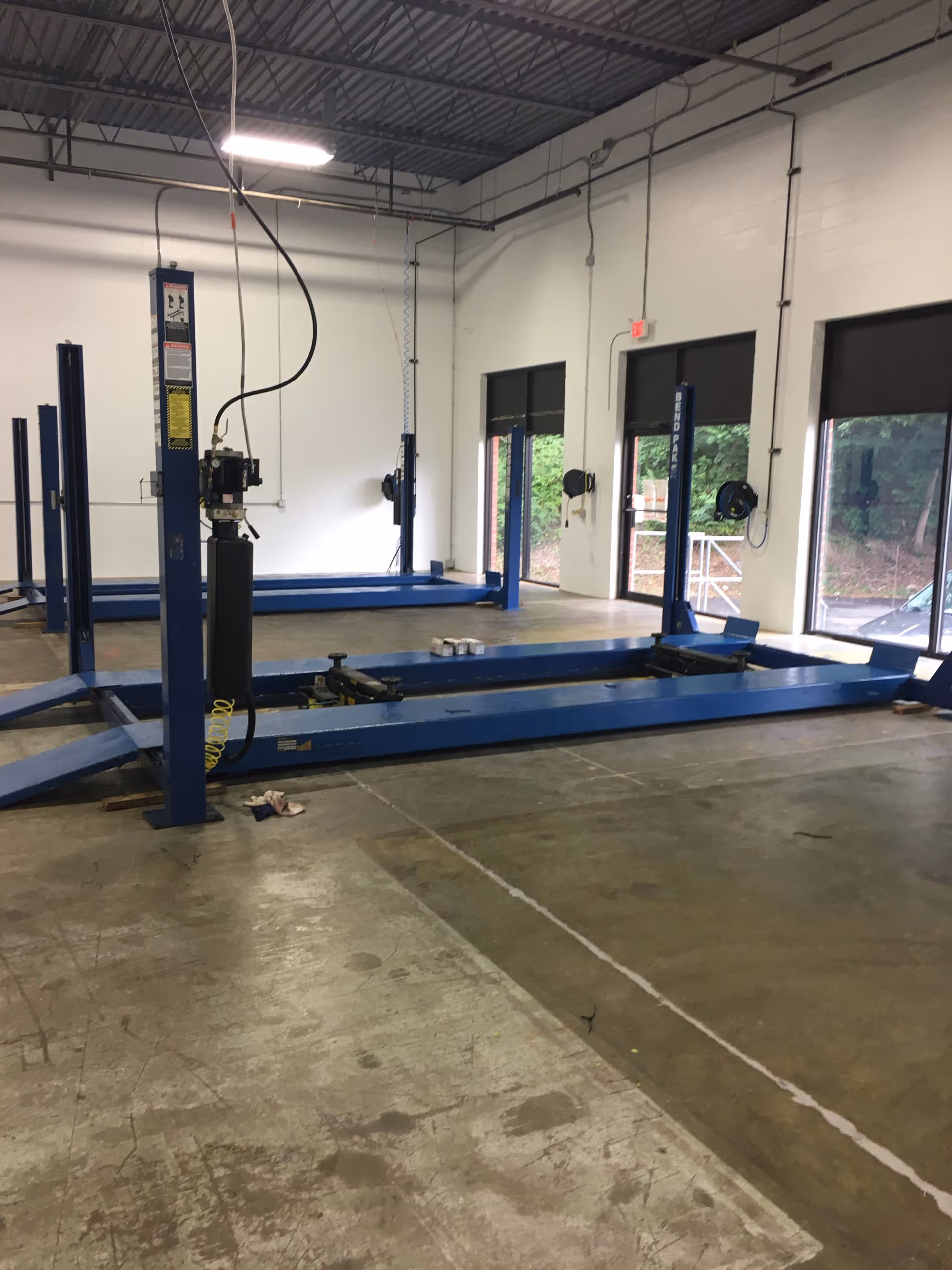 Interior of MobilityWorks workshop with blue hydraulic lifts, equipment, and large windows.