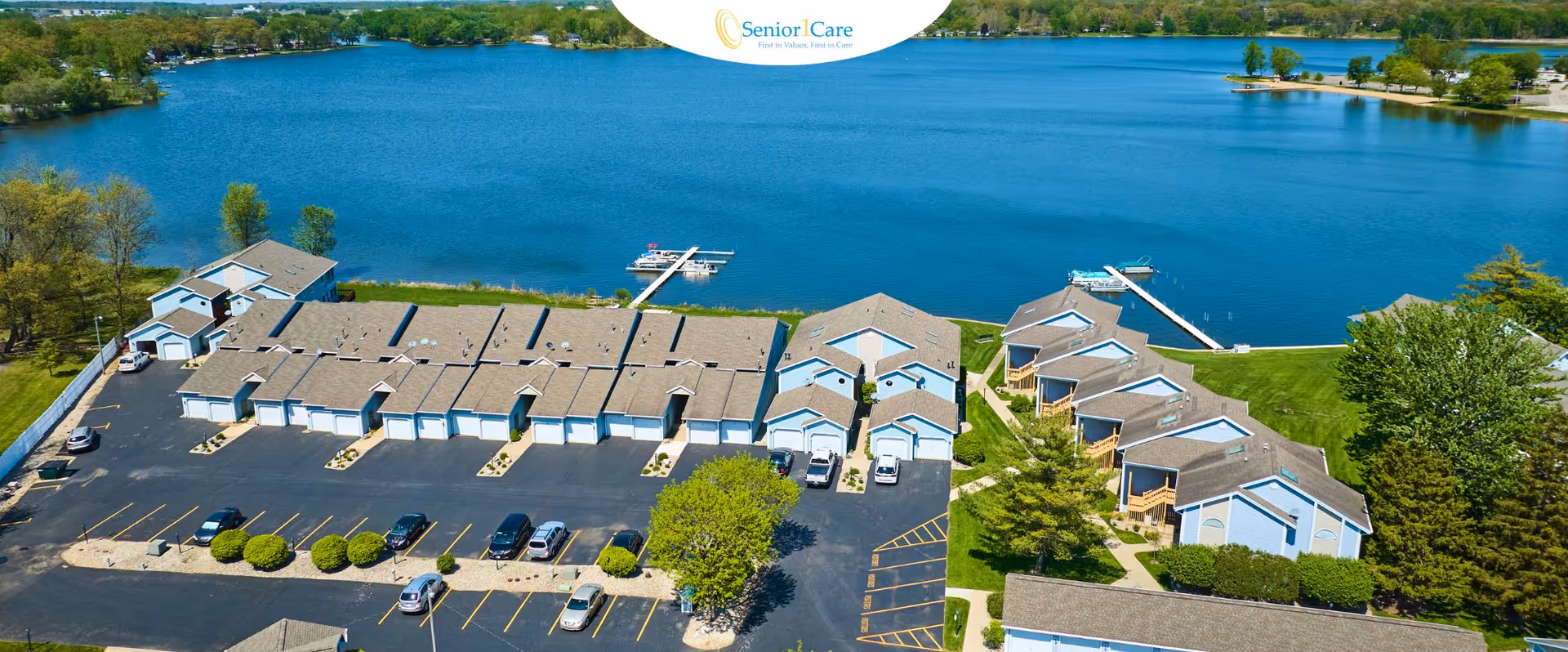 Aerial view of a multi-building senior living campus beside a large blue lake.