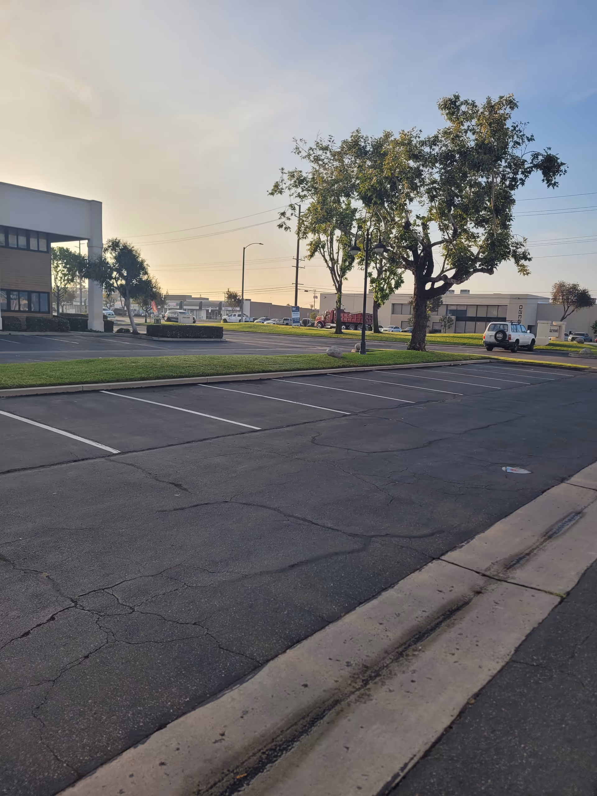 Parking lot and building exterior with trees under a clear sky.