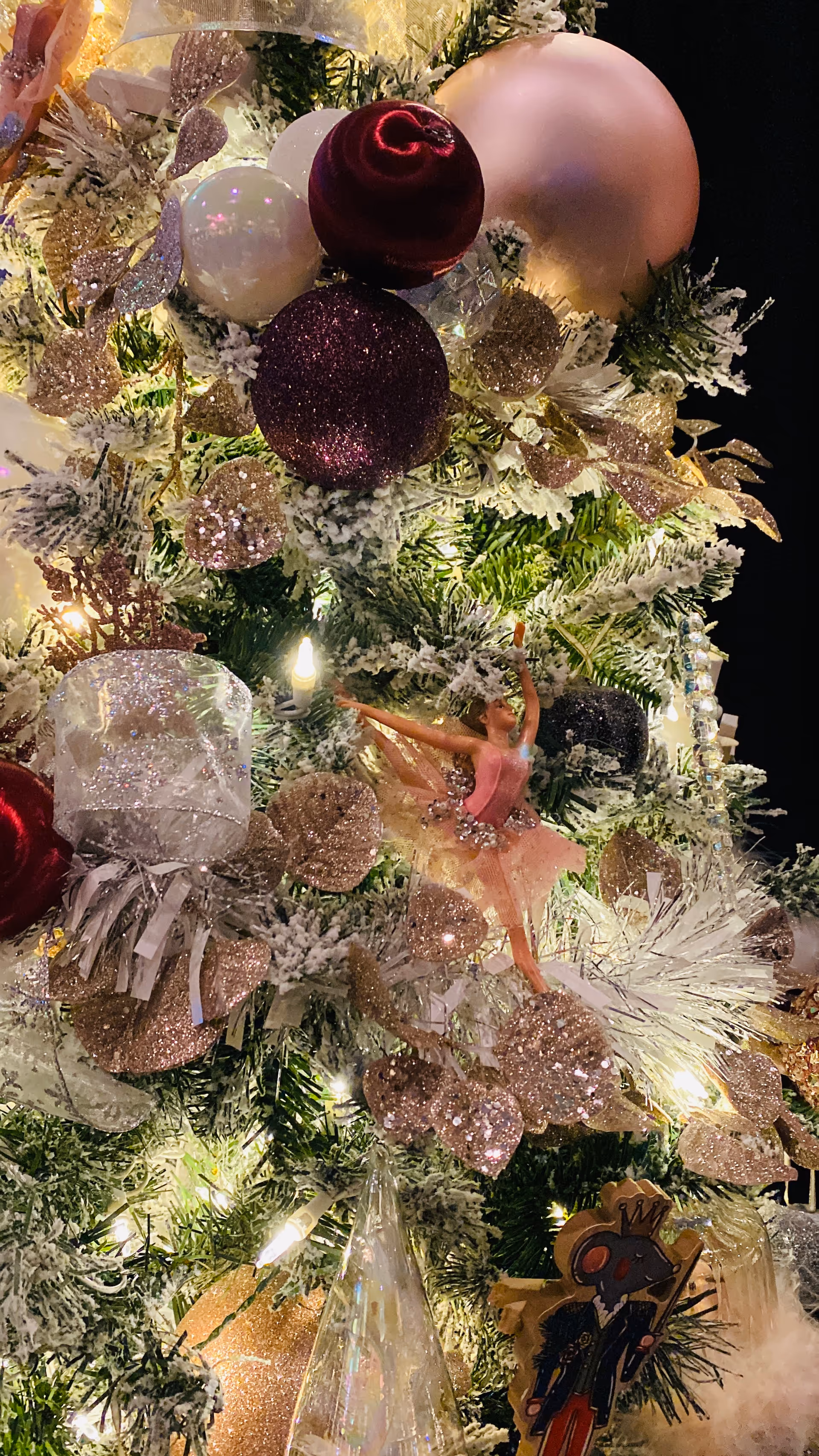 Decorated Christmas tree with pink glitter ornaments and lights indoors.