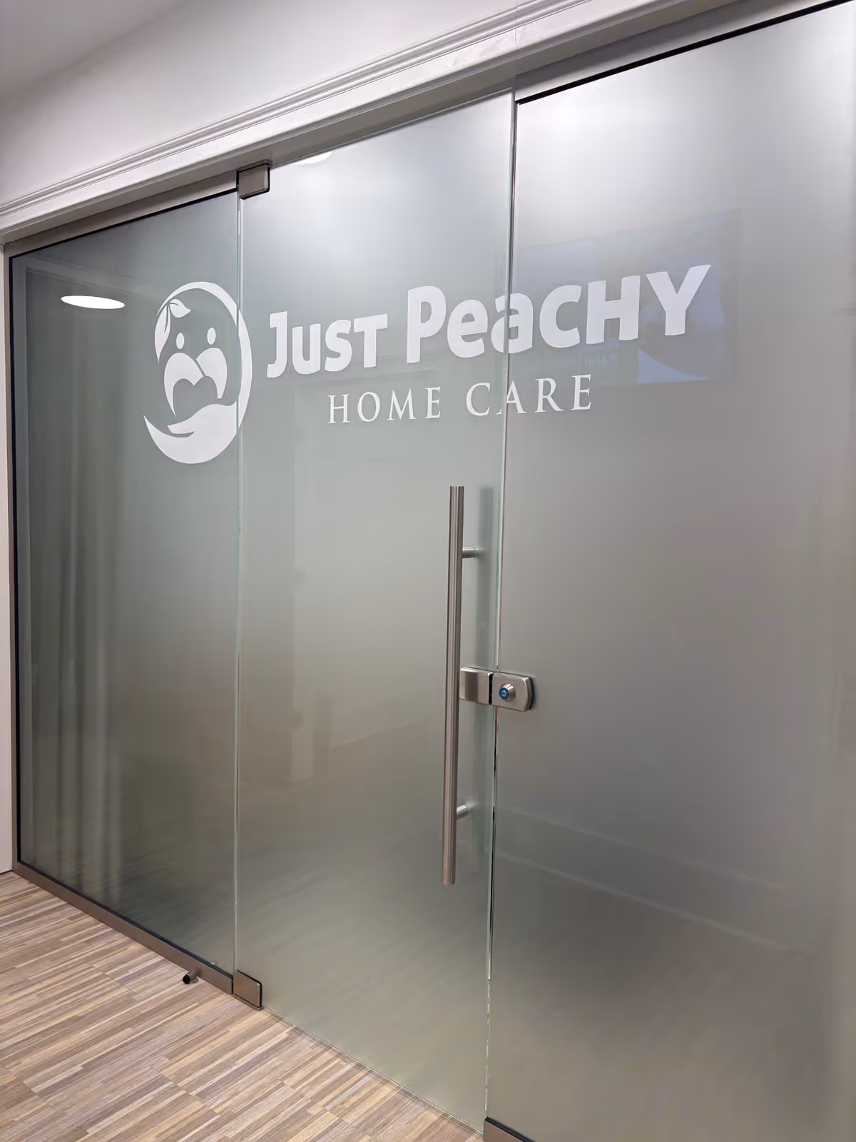 Frosted glass doors with the Just Peachy Home Care logo and vertical door handle.