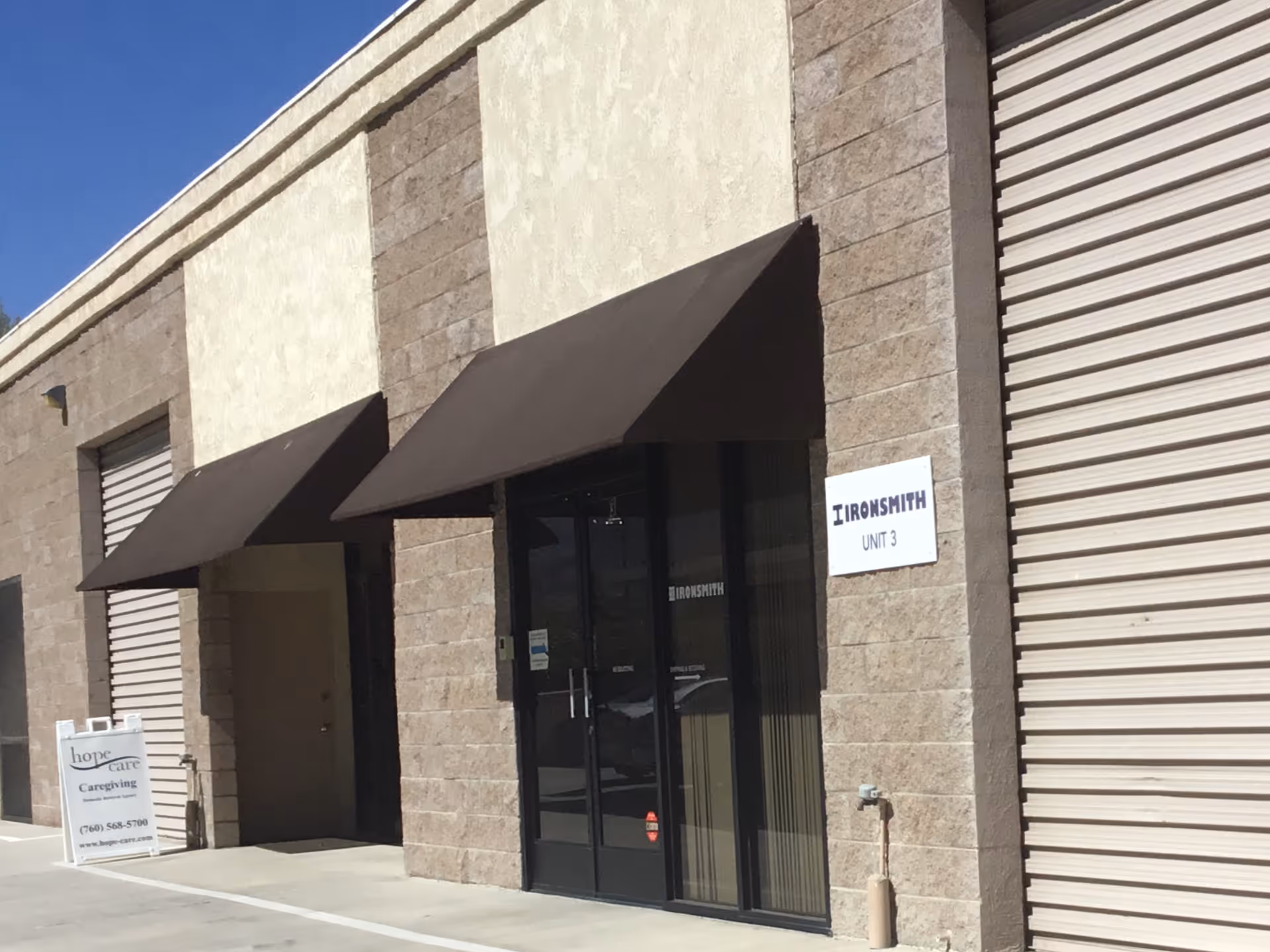 Exterior view of a facility entrance with brown awnings and signage.