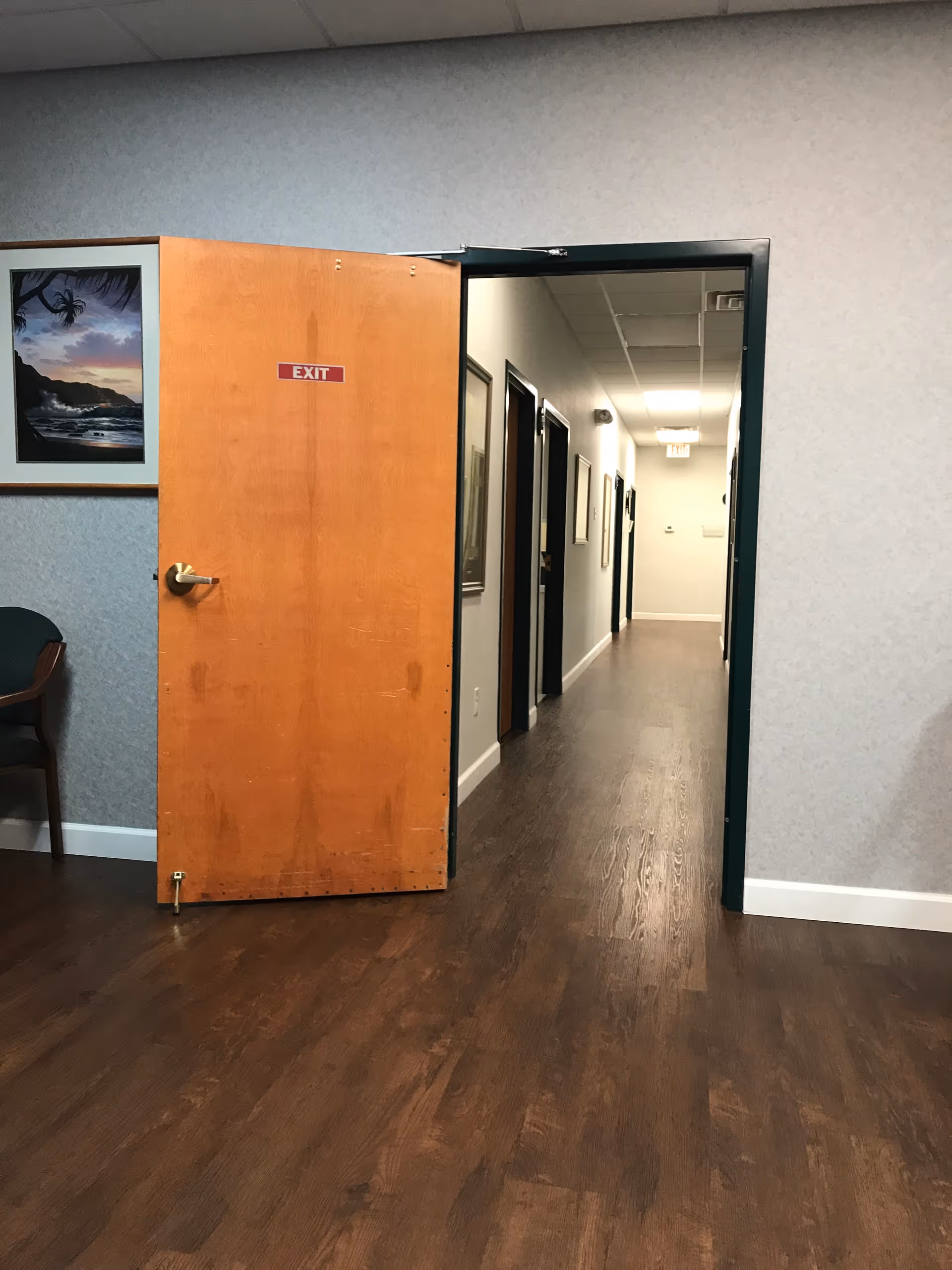 Interior hallway of a senior facility with an open door, corridor, and exit sign.