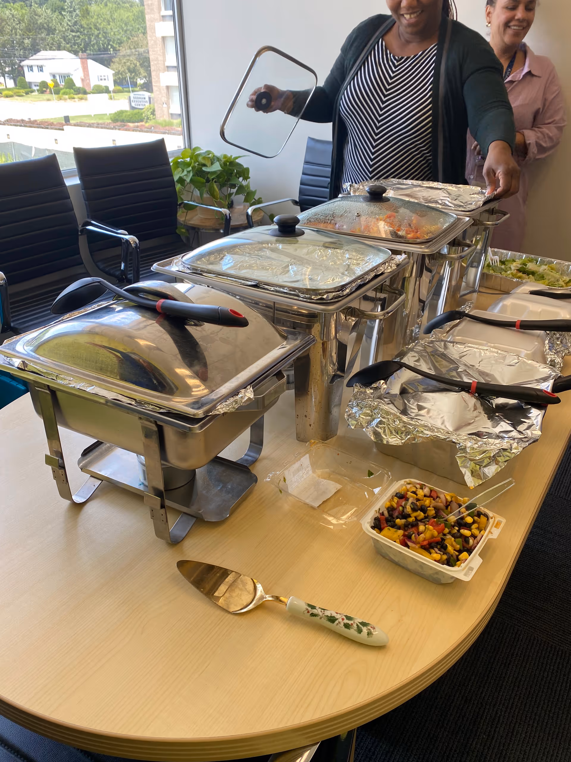 Buffet setup with chafing dishes and a salad tray in a dining room.