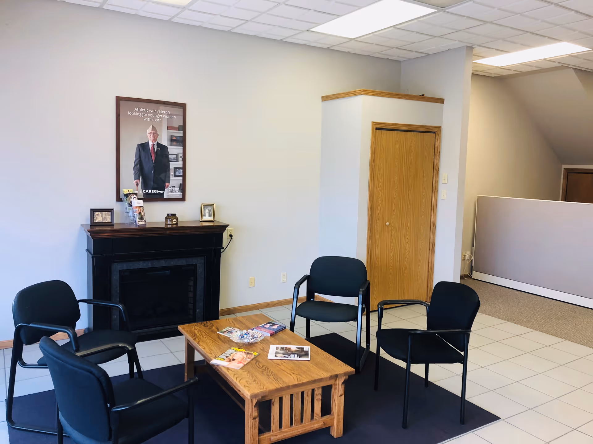 A small senior living facility lobby with five black chairs around a wooden coffee table.