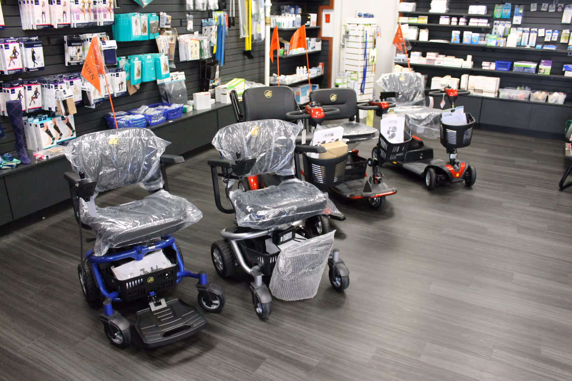 Interior showroom with several mobility scooters on display and shelves of medical supplies.