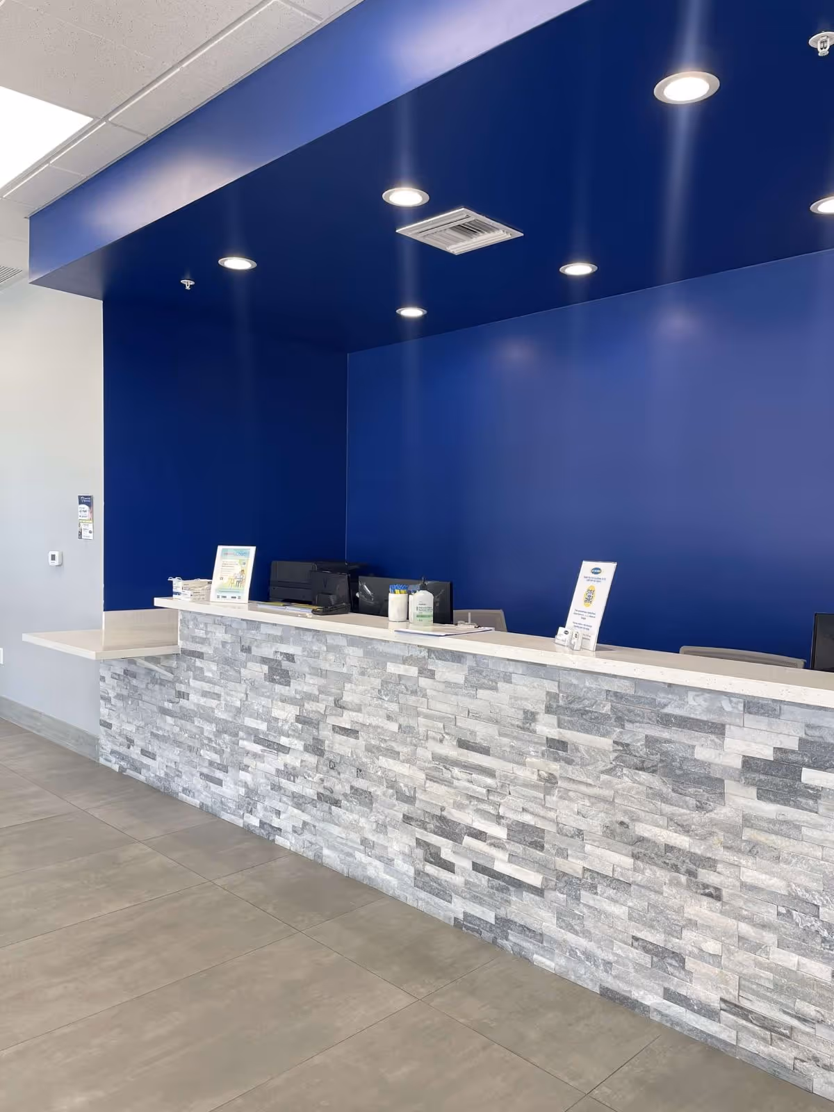 Modern reception desk with a stone facade against blue walls inside a MY DR NOW facility.