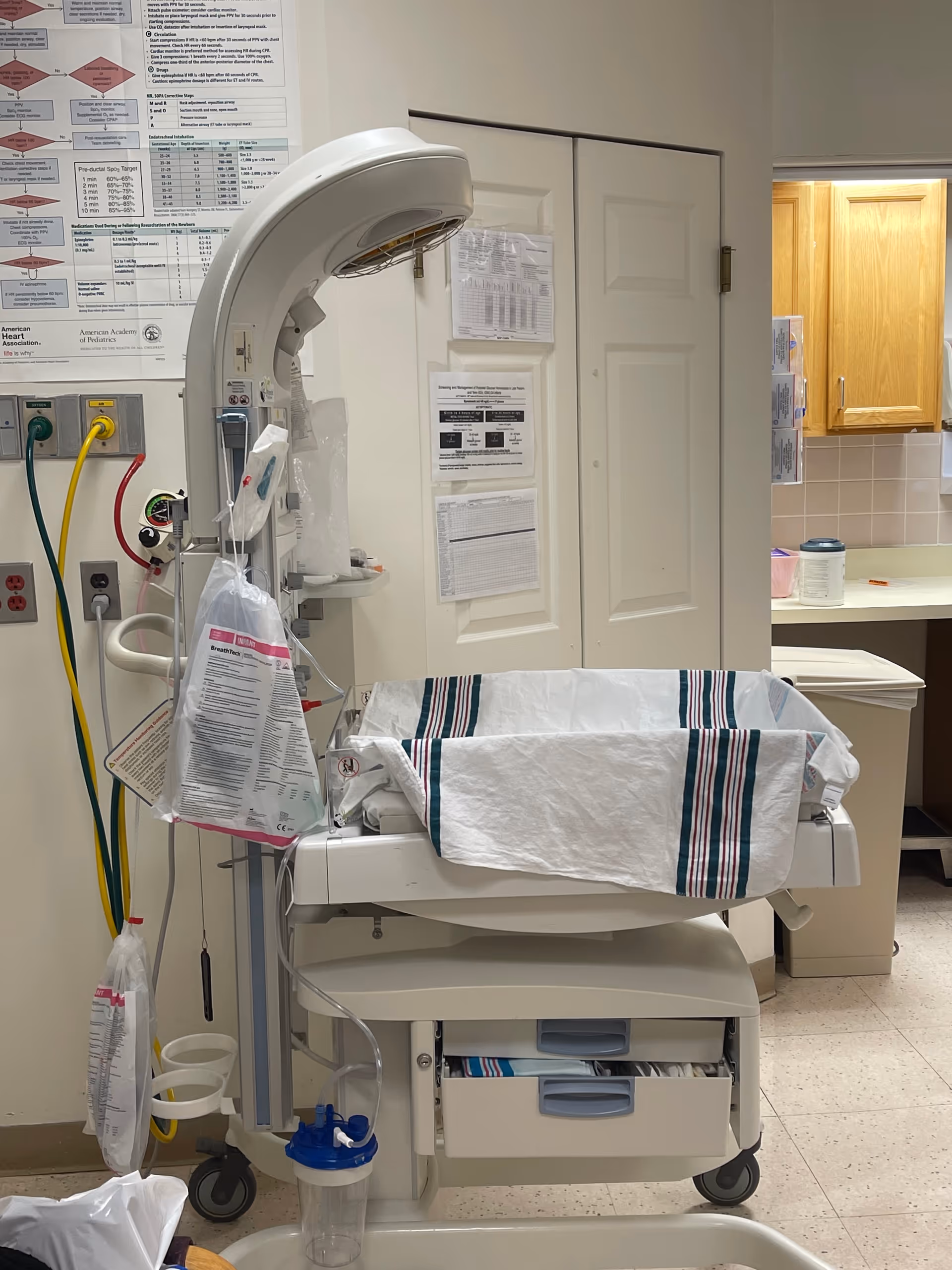 Hospital neonatal incubator with medical equipment in a room.