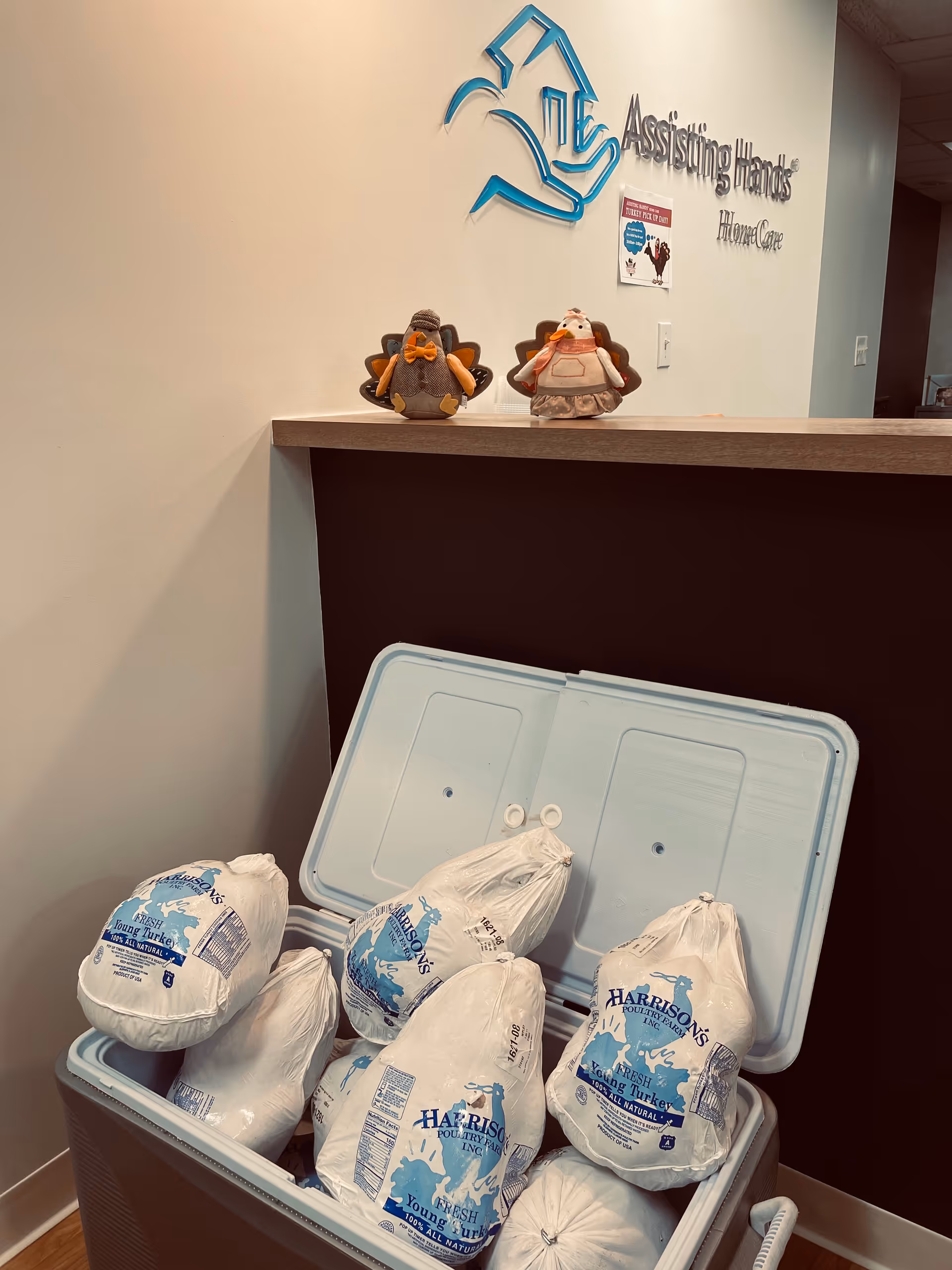 Lobby reception area with Assisting Hands Home Care logo and a cooler filled with frozen turkeys.