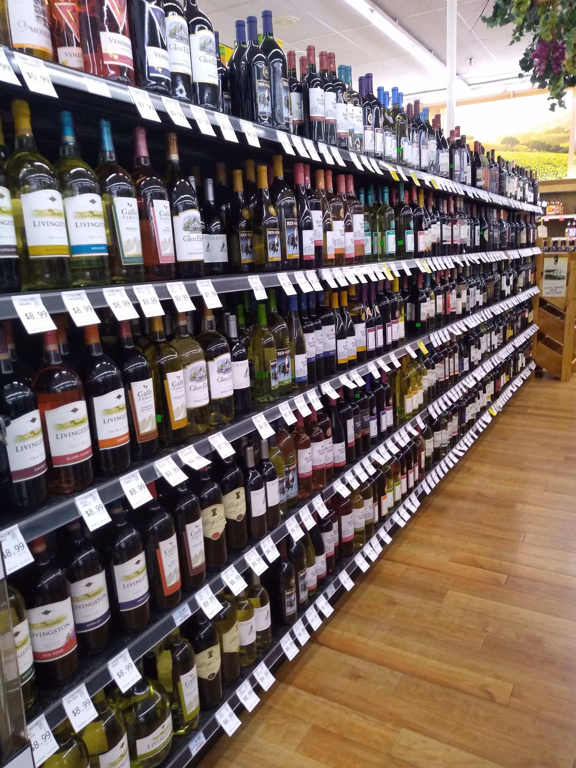 Aisle of wine bottles on shelves in a well-lit store interior.