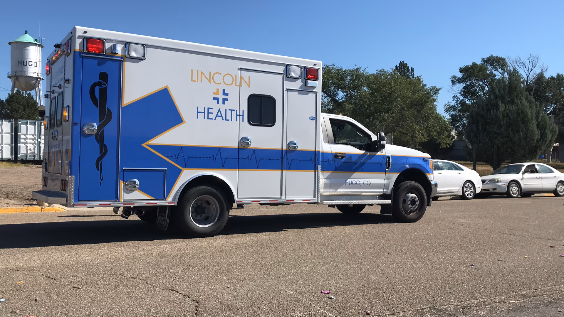 An ambulance with Lincoln Health branding parked in a lot beside trees
