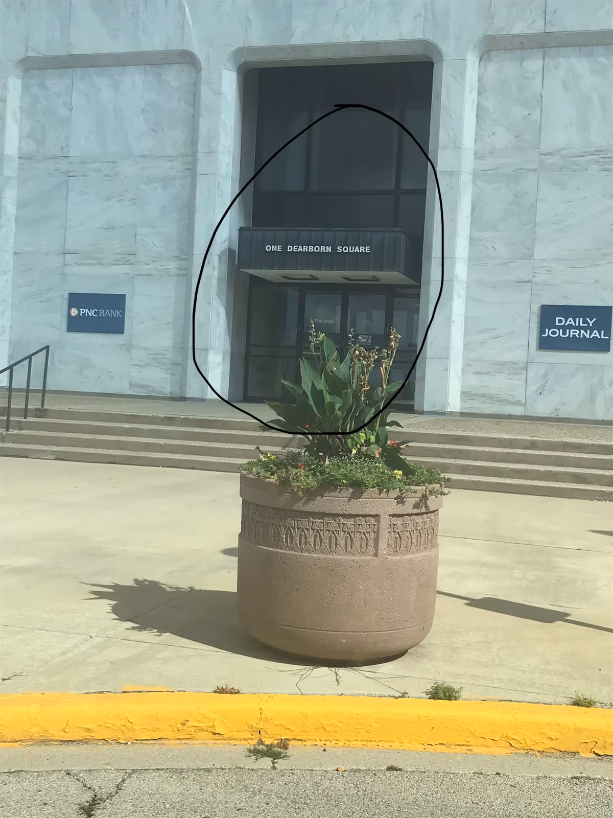 Exterior of a marble building with glass doors and a large planter.