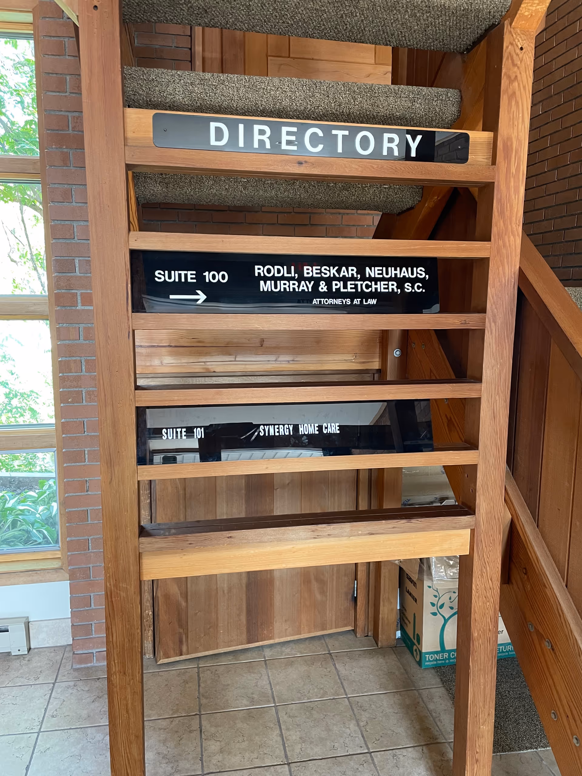 Wooden interior directory area with suite numbers and staircase, no people visible.