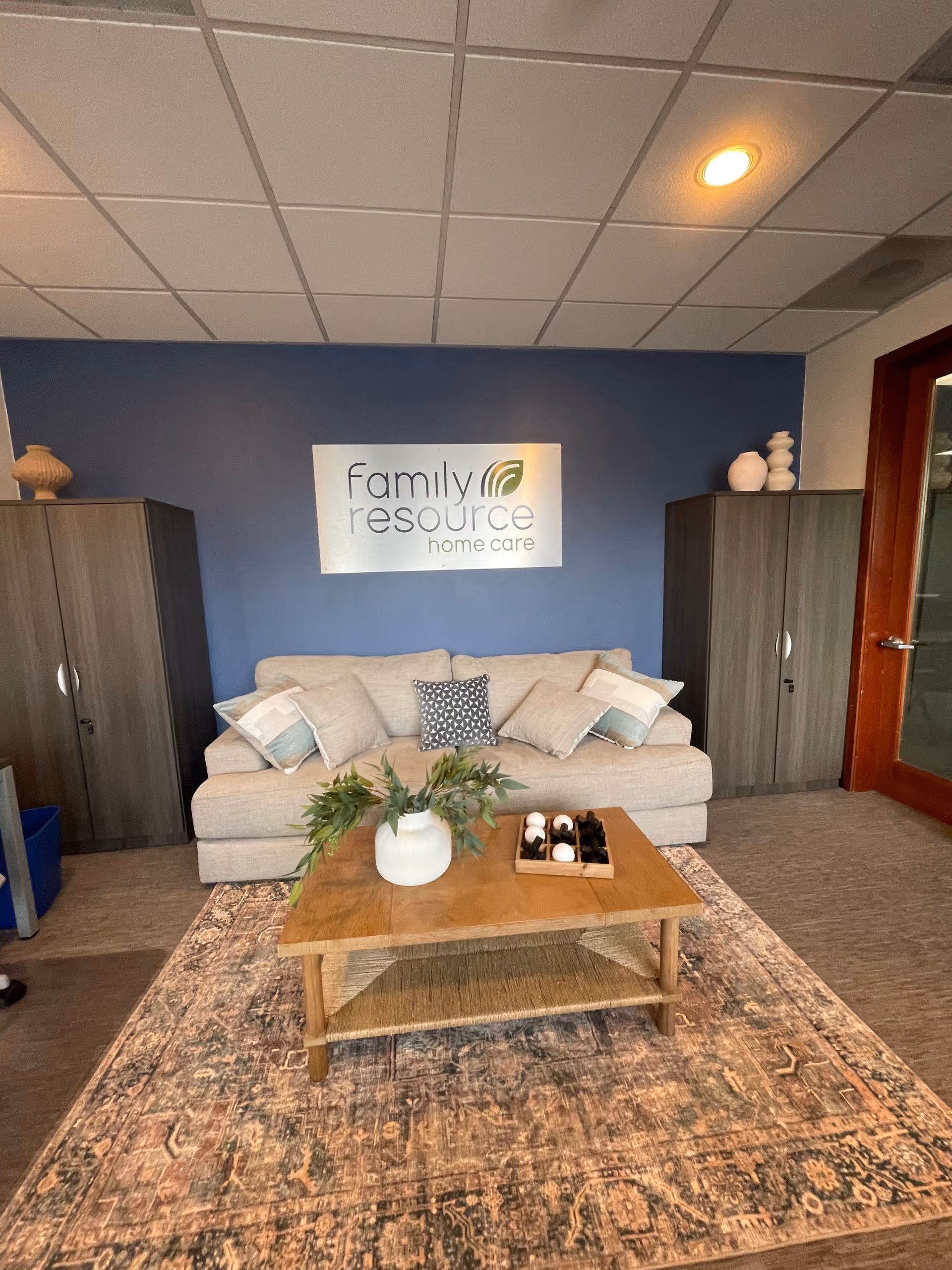 Lobby seating area with sofa, coffee table, cabinets, and a Family Resource Home Care sign.