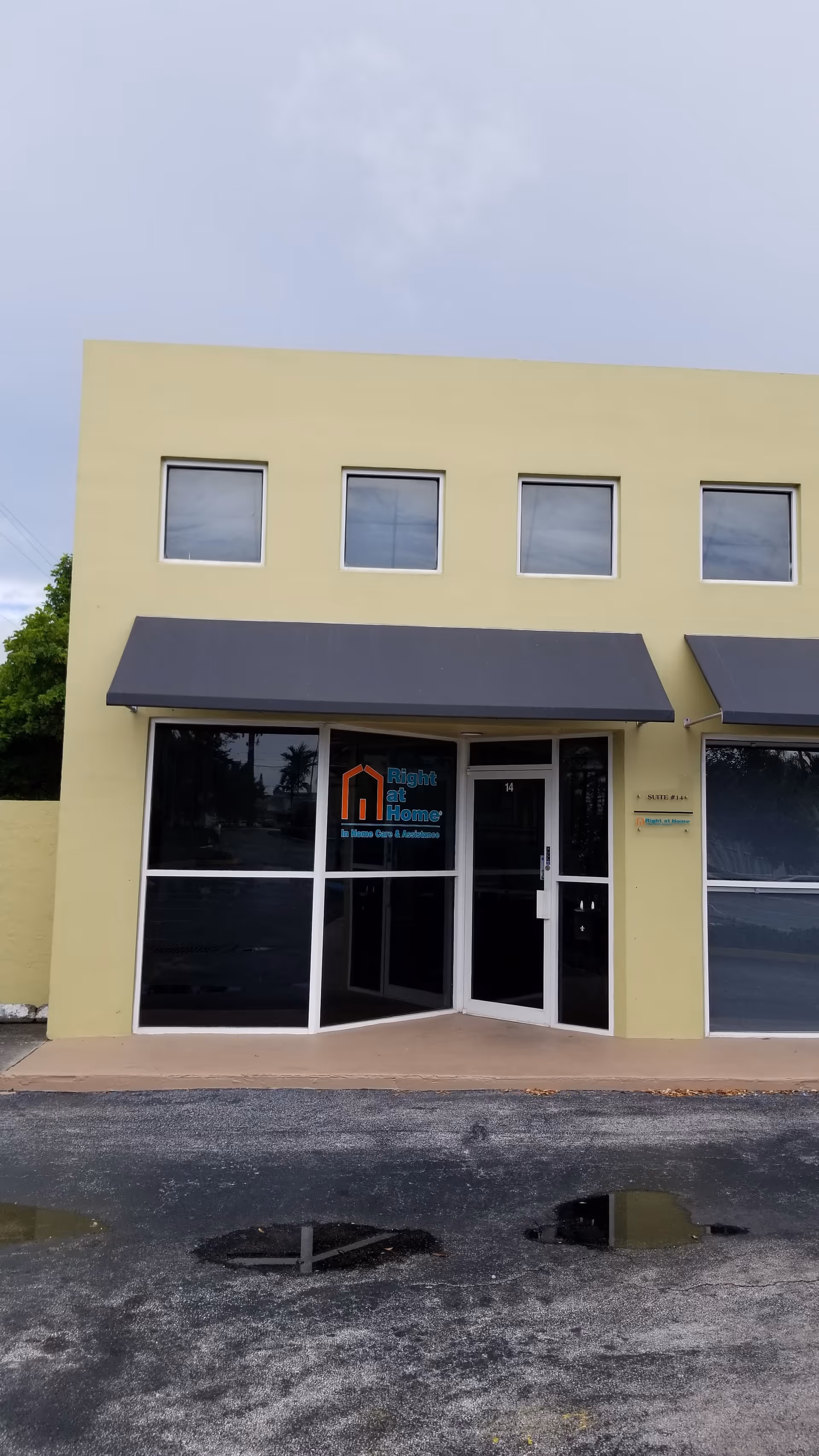 Yellow two-story building with glass entrance, awnings, and a Right at Home sign.