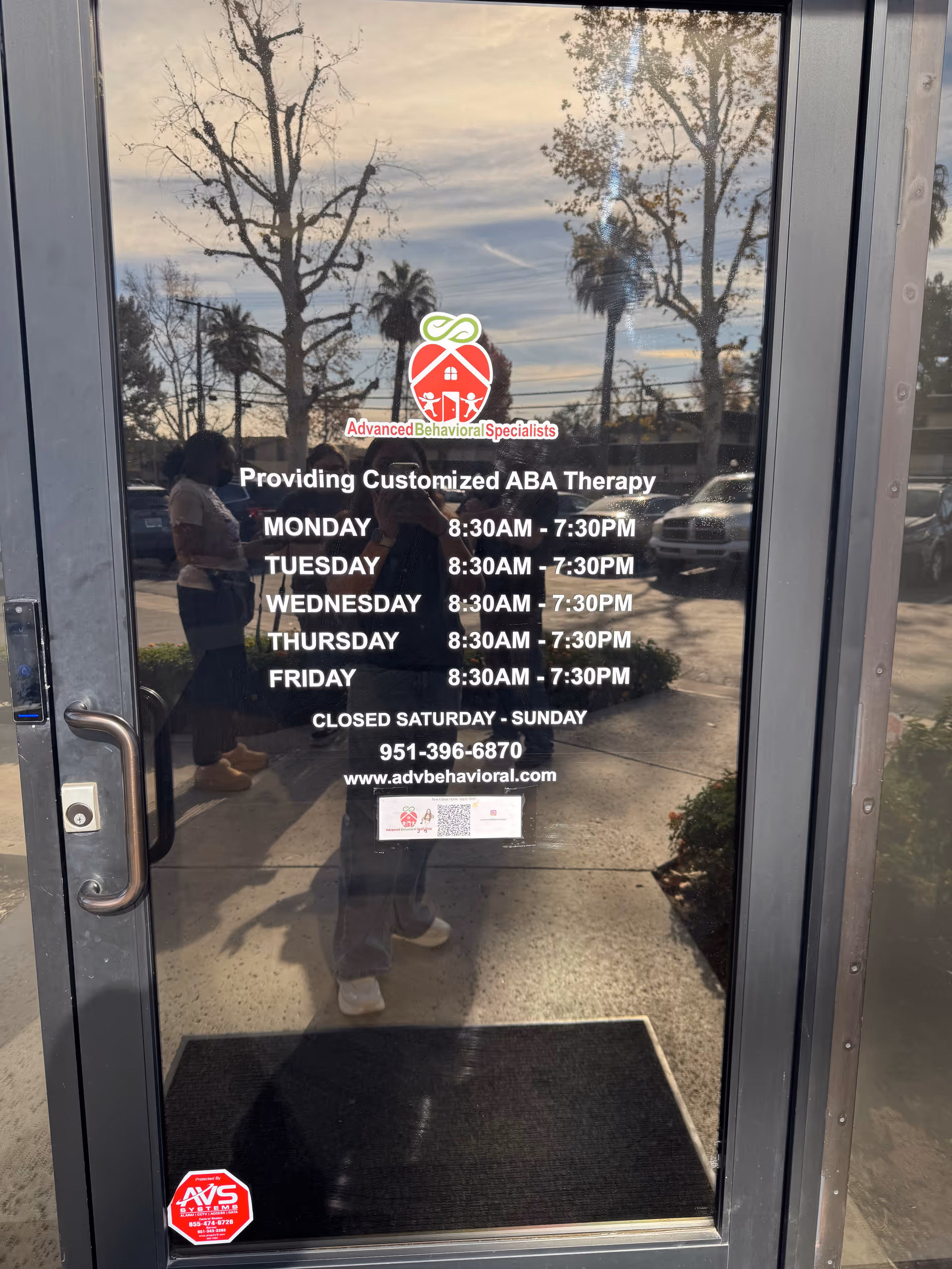 Glass door displays Advanced Behavioral Specialists logo and therapy hours.