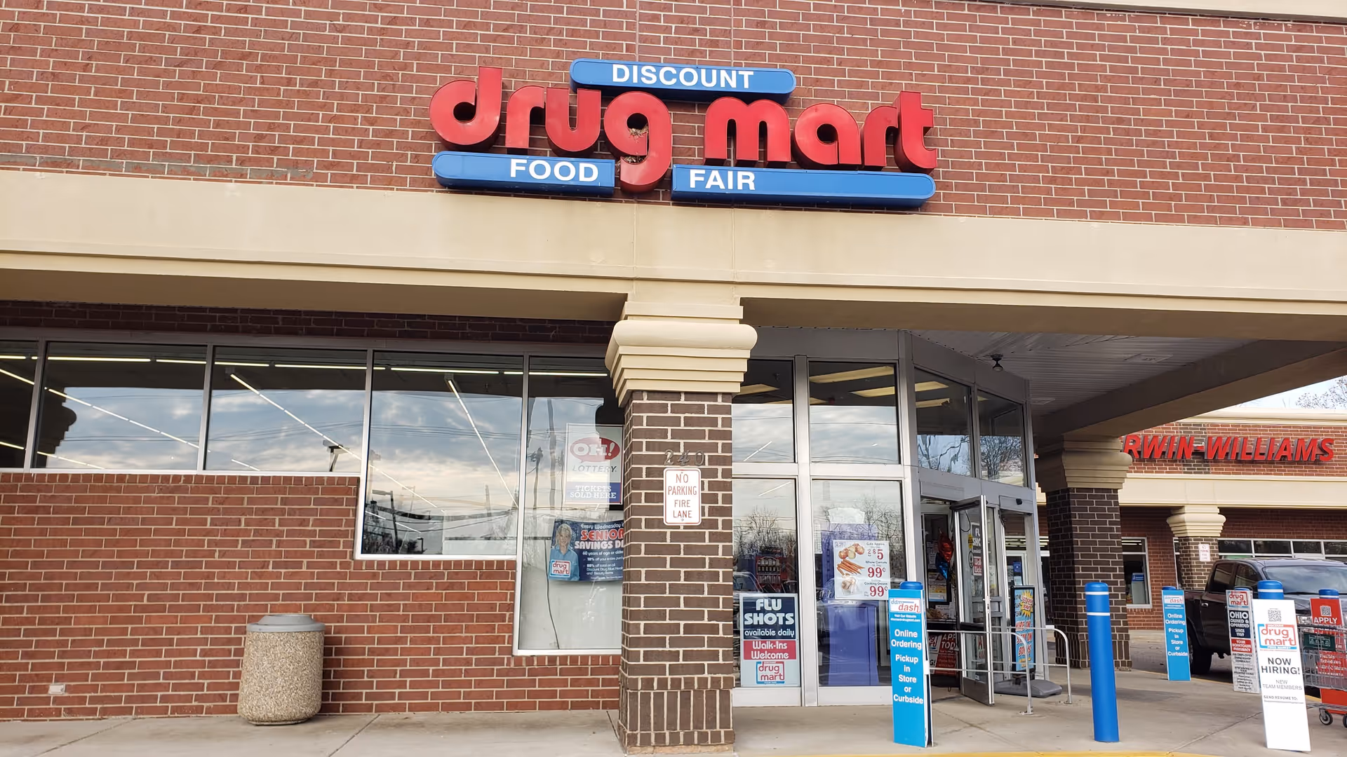 Brick storefront with large glass windows and a prominent Discount Drug Mart sign.