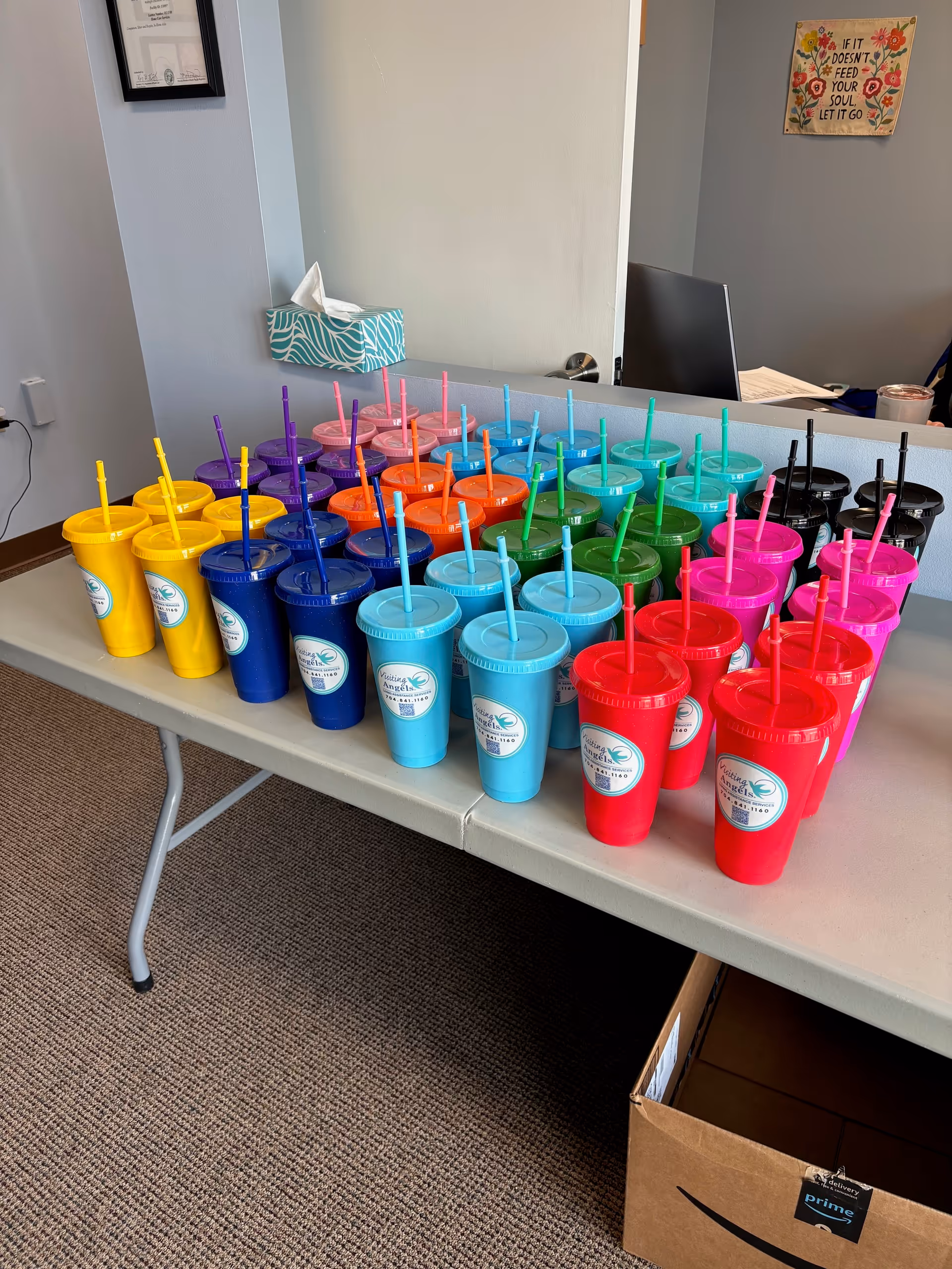 Row of colorful cups with straws arranged on a table in a reception area.