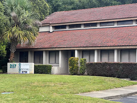 Exterior view of a red-tiled senior living facility with lawn and shrubs