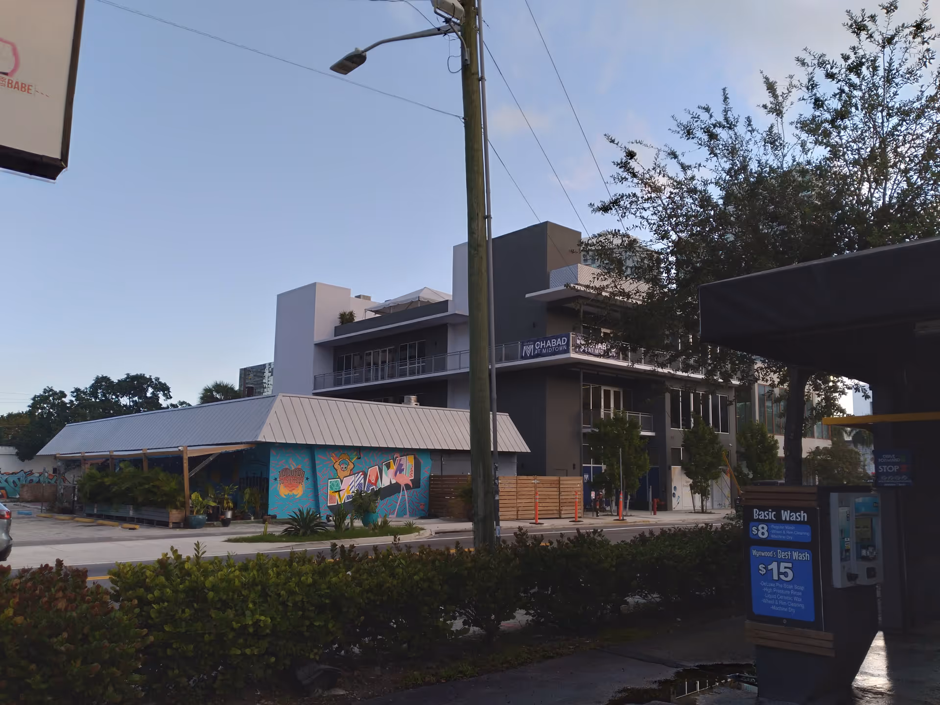 Exterior view of a modern building with mural, street, and utility pole in foreground.